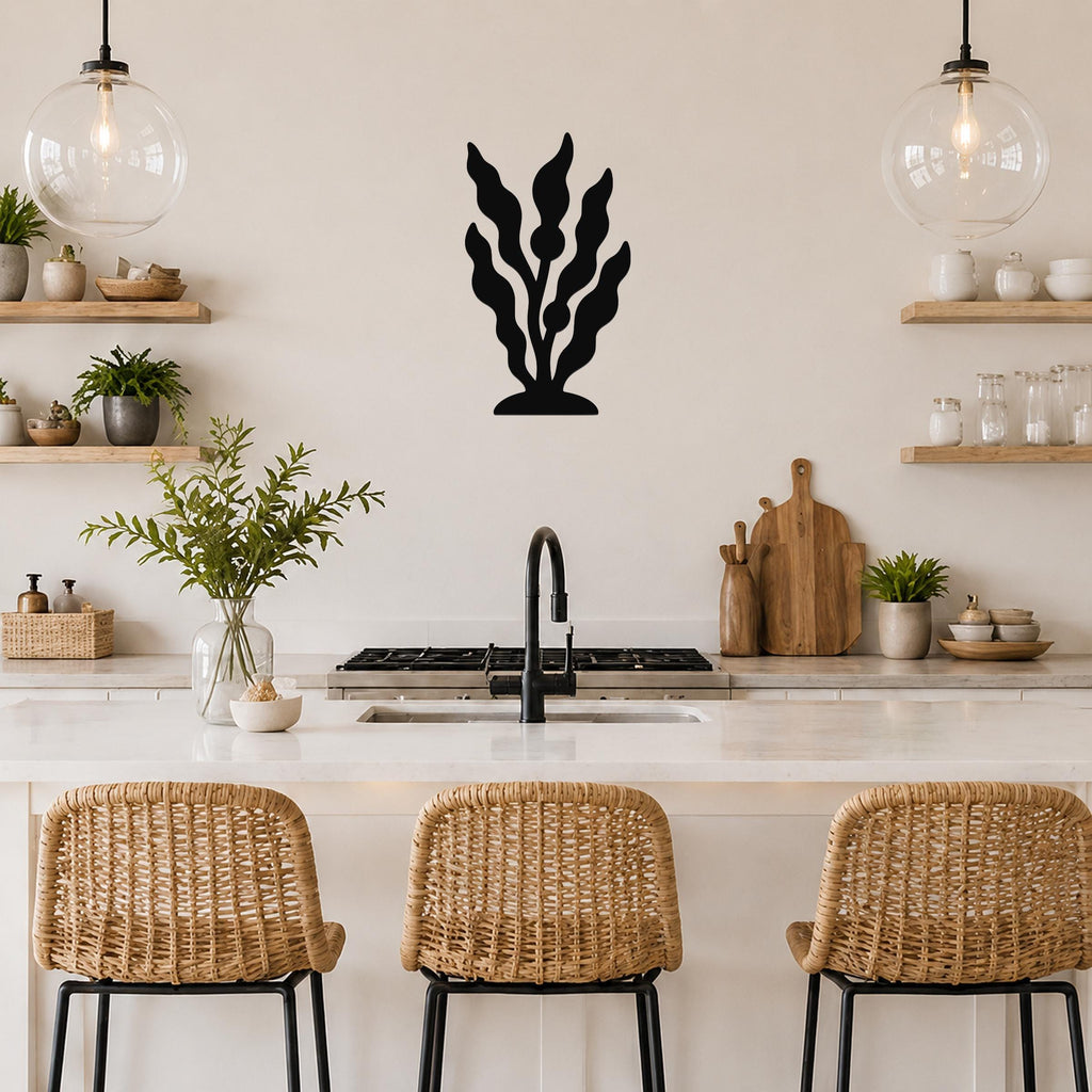 Black metal kelp wall art with leafy cutouts, mounted on a kitchen wall above a counter between two glass pendant lights.