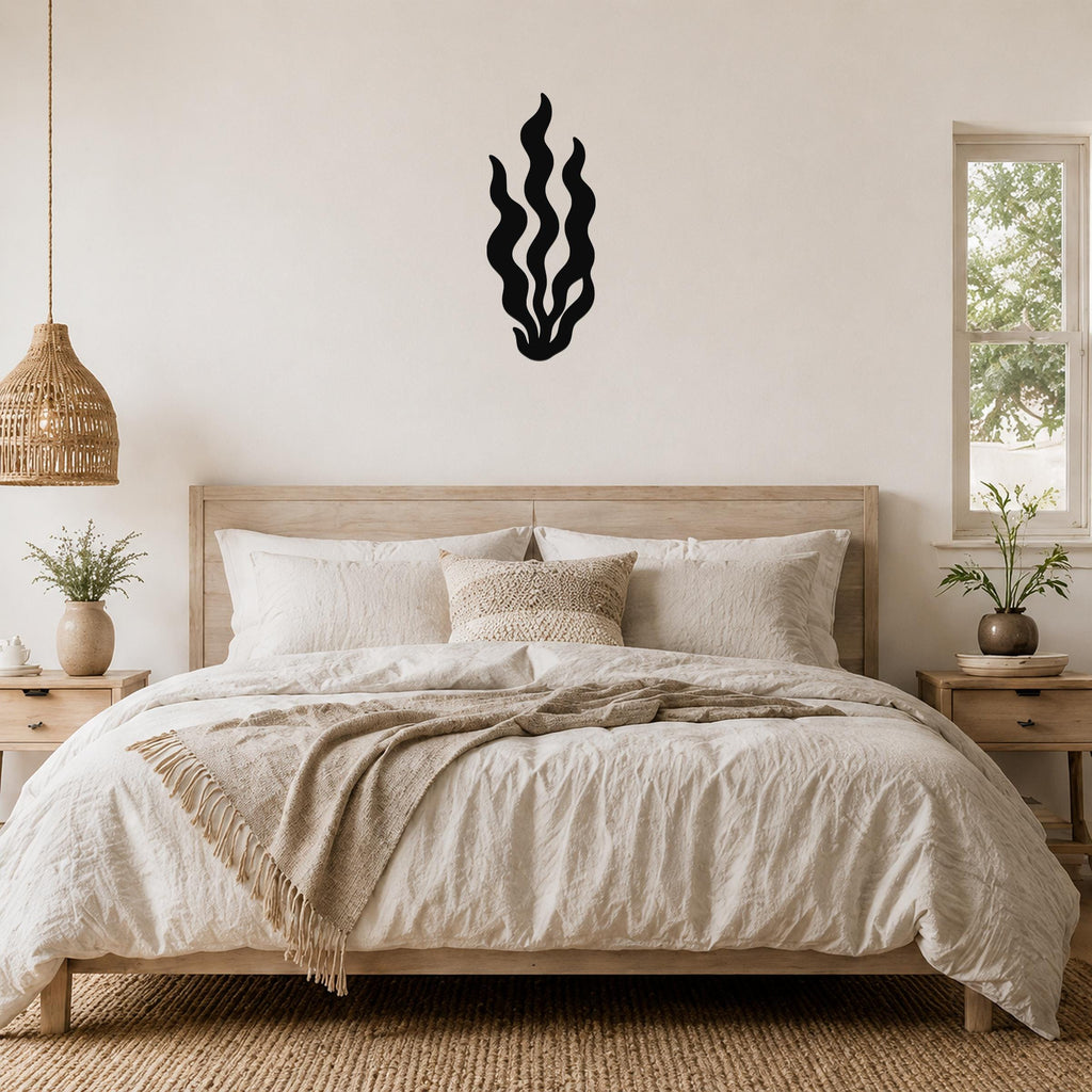 Black metal kelp wall art with flowing wavy cutouts, mounted above a wooden bed in a neutral bedroom.