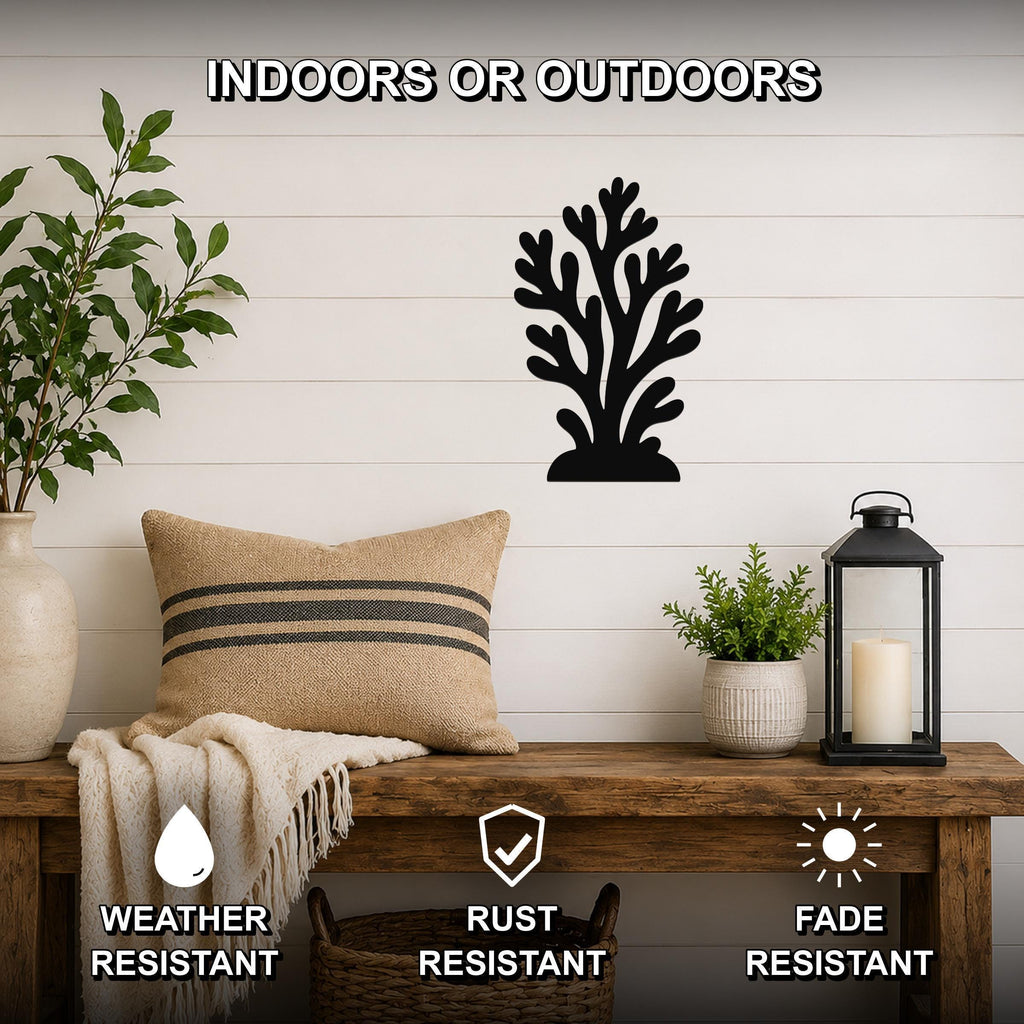 Black metal coral wall art with intricate branch cutouts, mounted on a white shiplap wall above a wooden bench in a coastal-style living space.