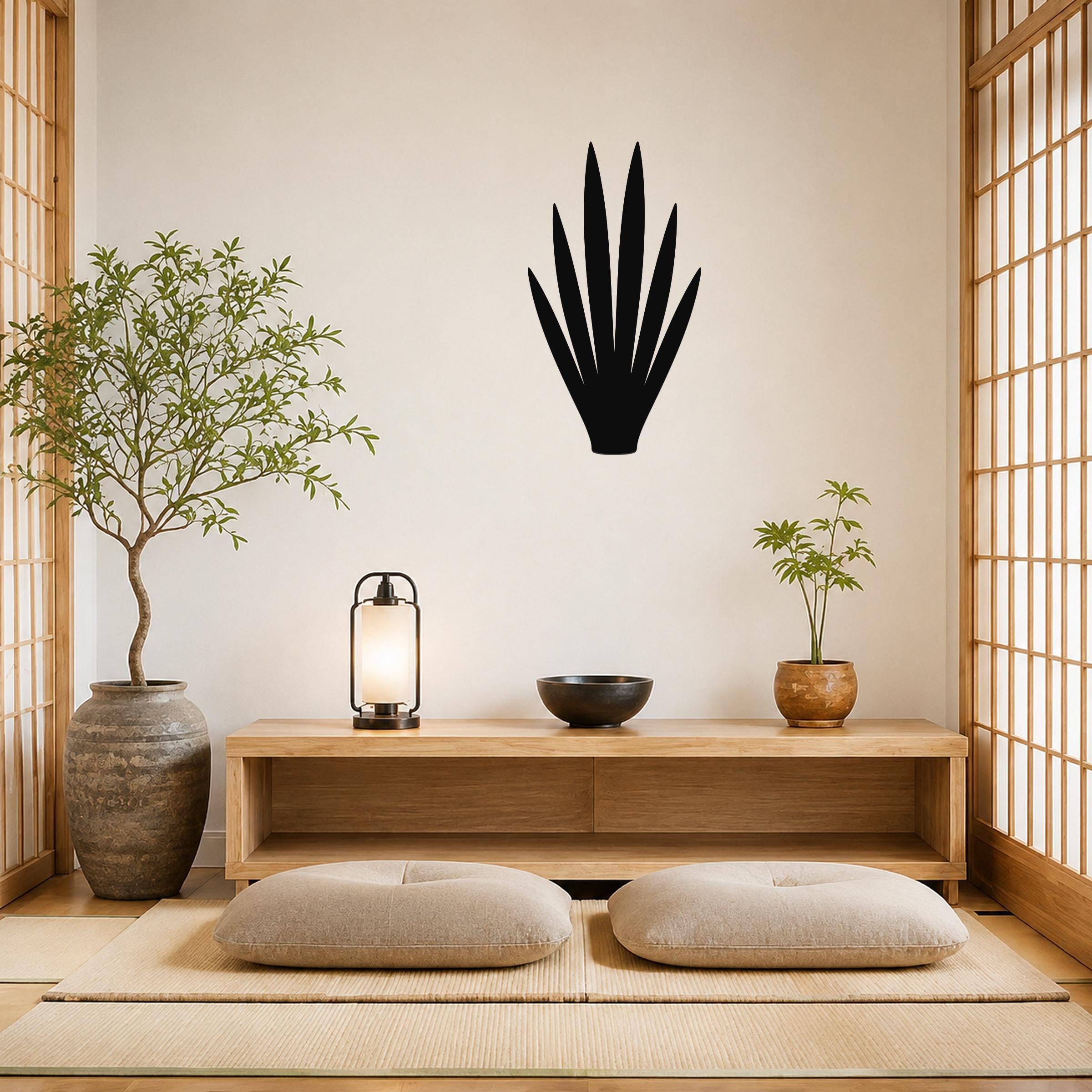 Black metal yucca leaf wall art silhouette mounted on a light-colored wall above a wooden console in a minimalist living room.