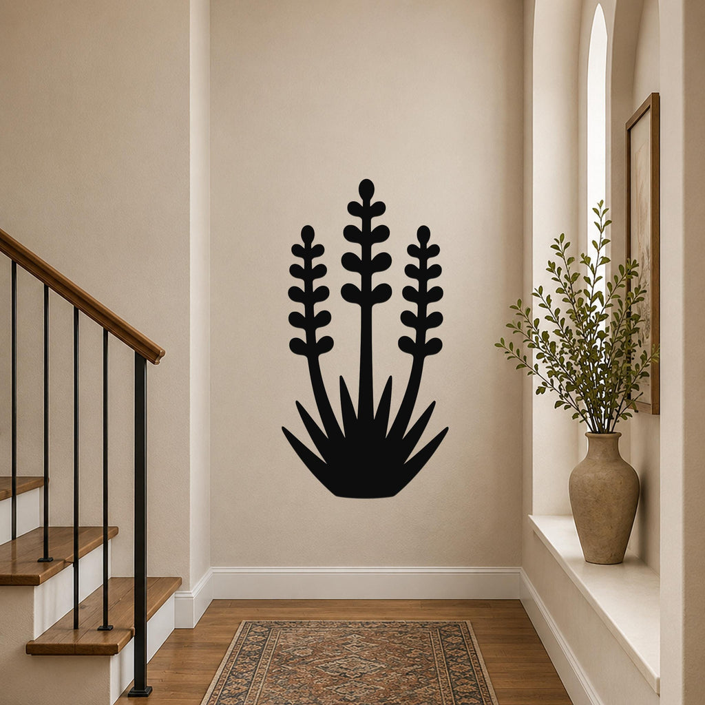 Black metal yucca wall art with layered leaf cutouts, mounted on a hallway wall above a patterned rug near a staircase.