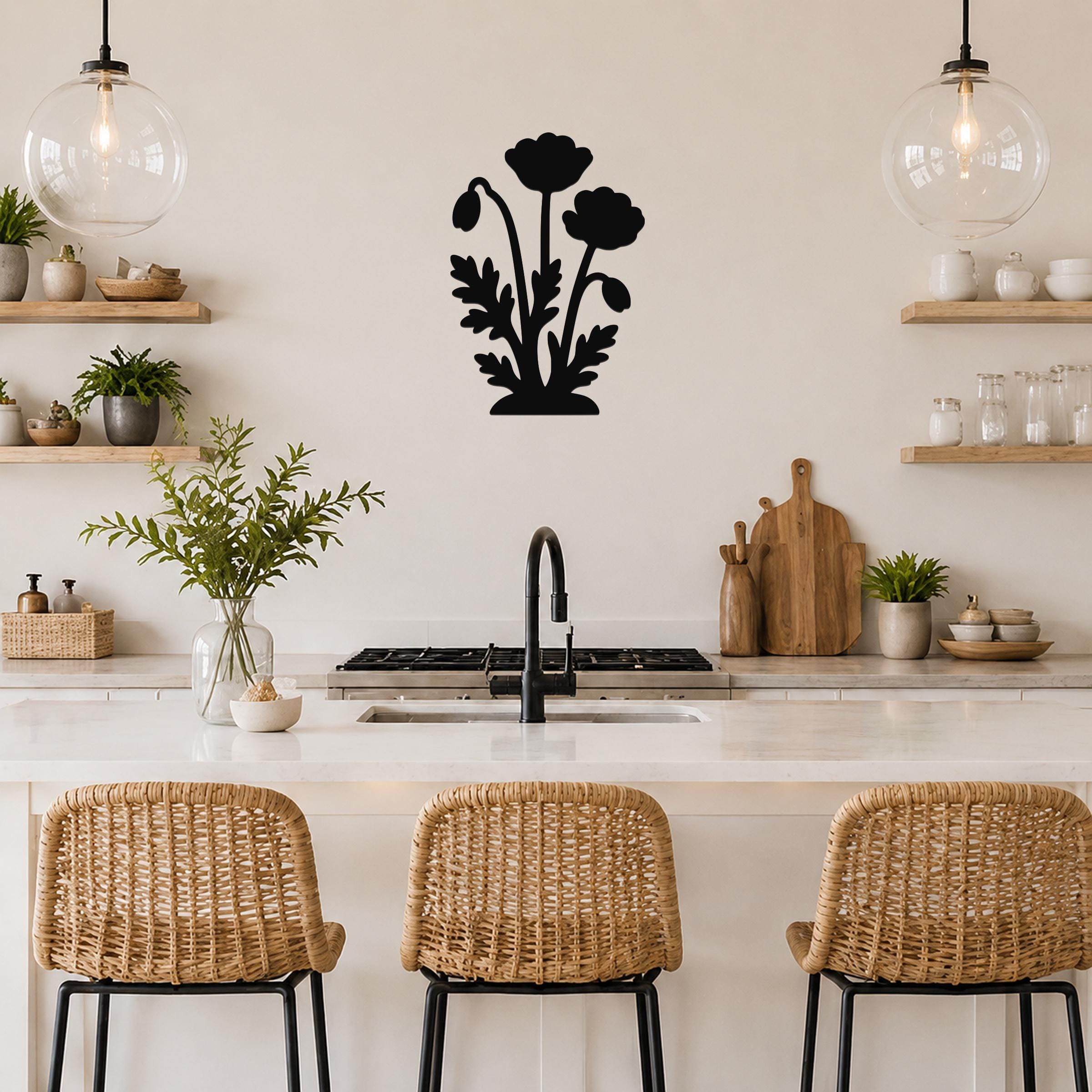 Black metal wall art with a floral silhouette of three poppies and leaves, mounted on a kitchen wall above a counter.