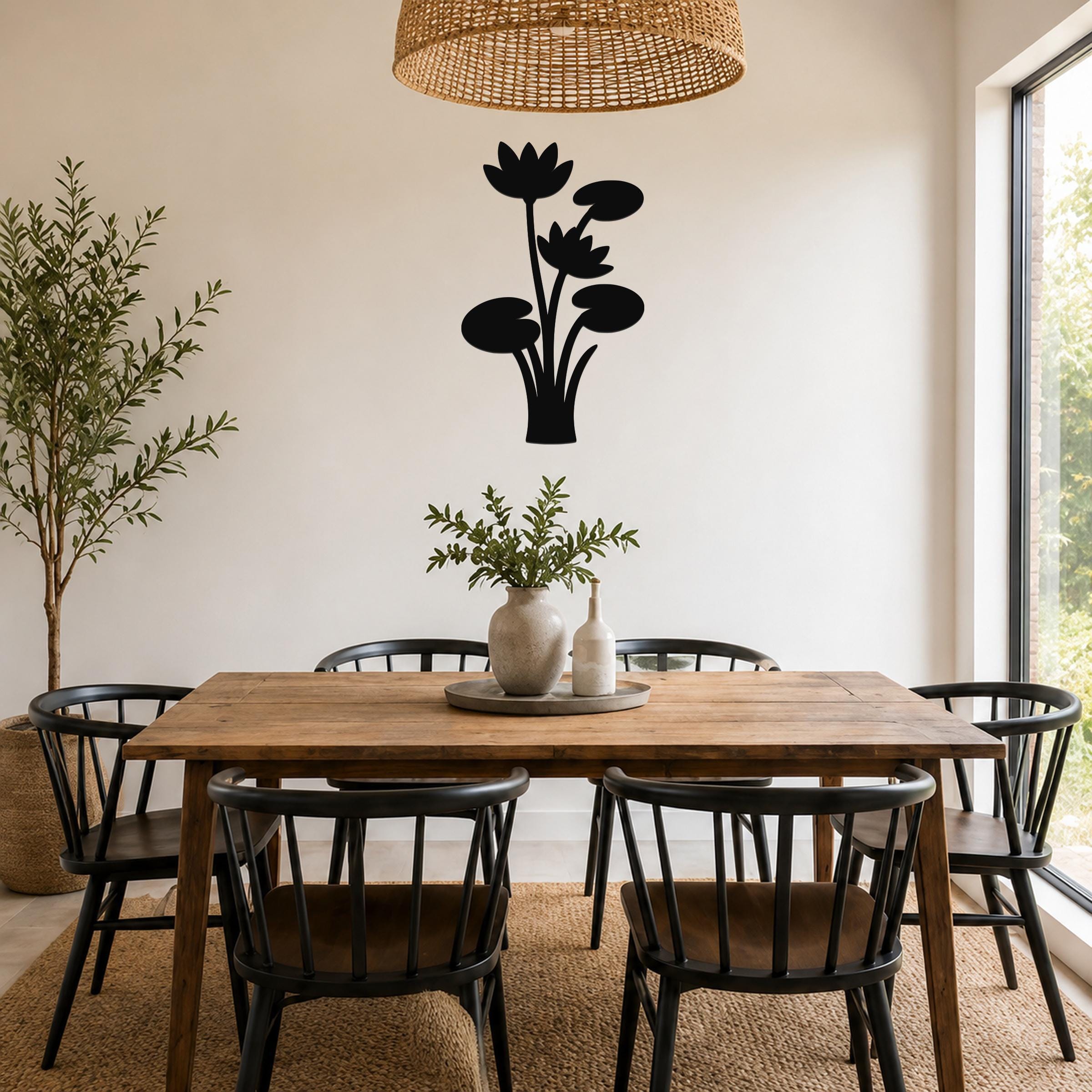 Black metal lotus water lily wall art with layered flower and leaf cutouts, mounted on a dining room wall above a wooden table.