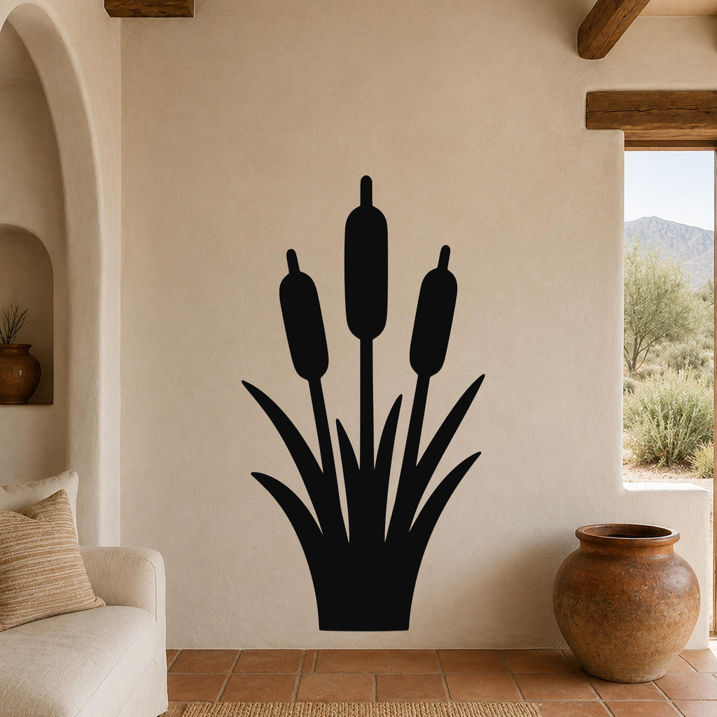 Black metal cattail wall art with three seed heads and leaf cutouts, mounted on a beige living room wall above a sofa.
