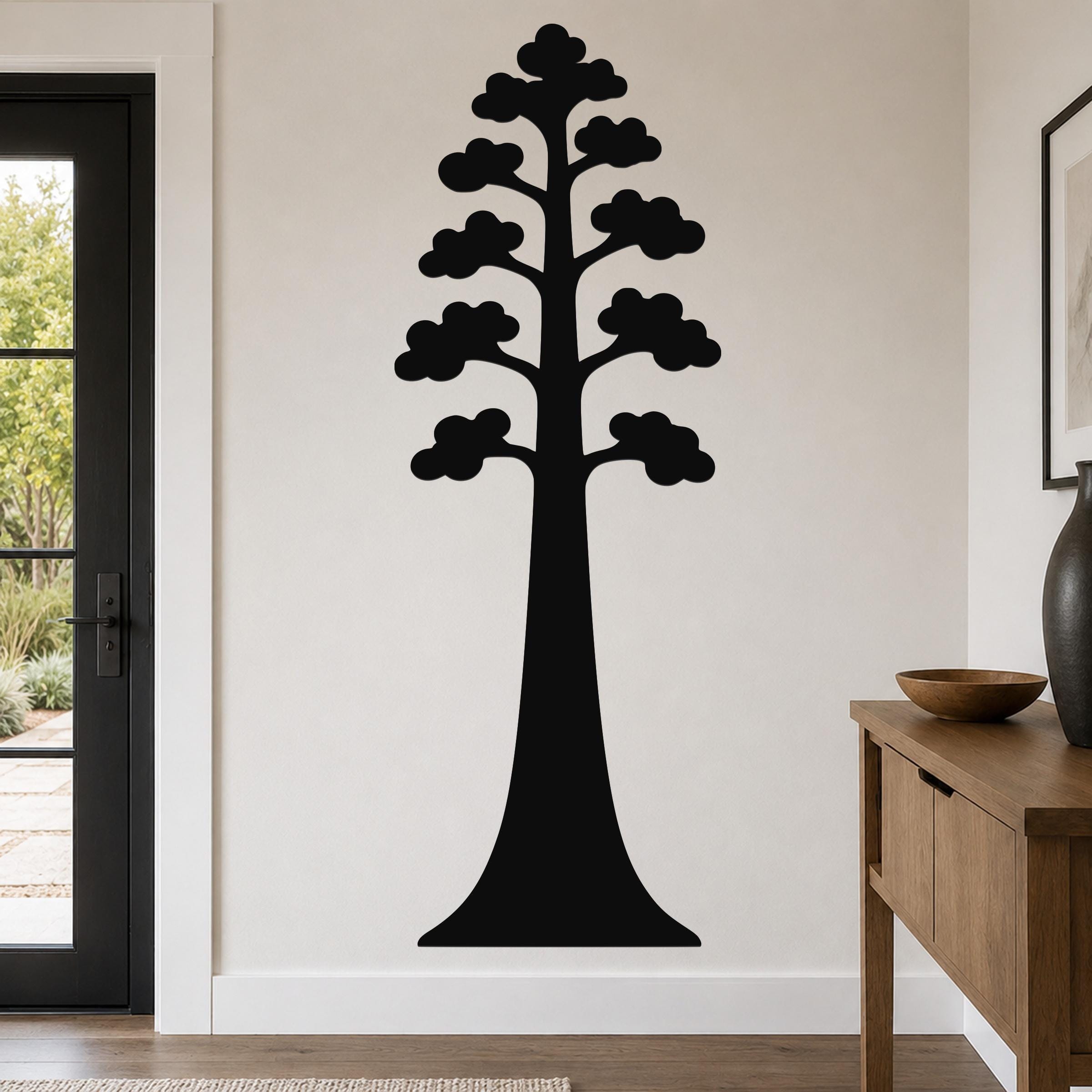 Black metal wall art in the silhouette of a sequoia tree with layered canopy cutouts, mounted on a living room wall above a wooden console table.