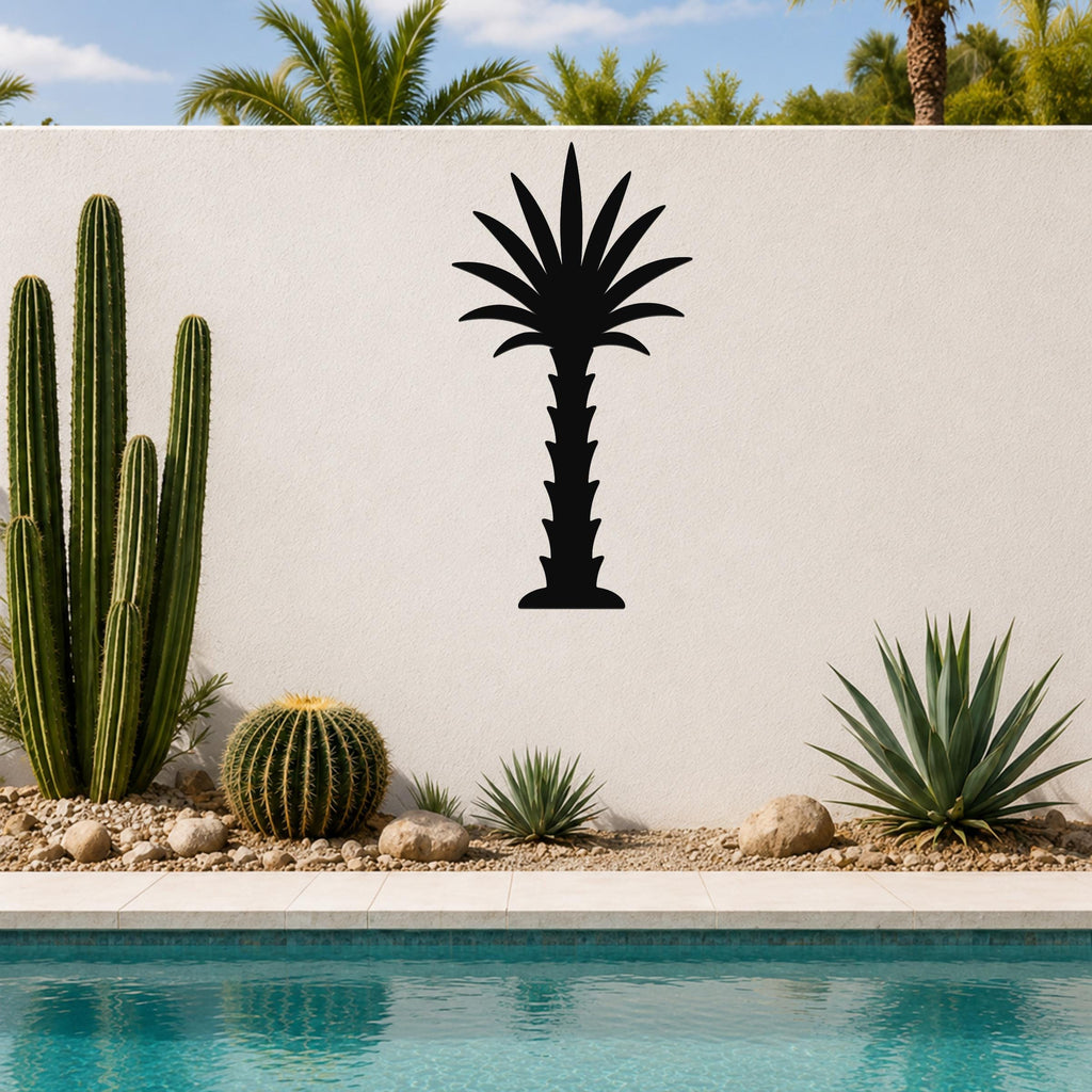 Black metal palm tree wall art silhouette mounted on a white outdoor wall above a pool, surrounded by cacti and desert plants.