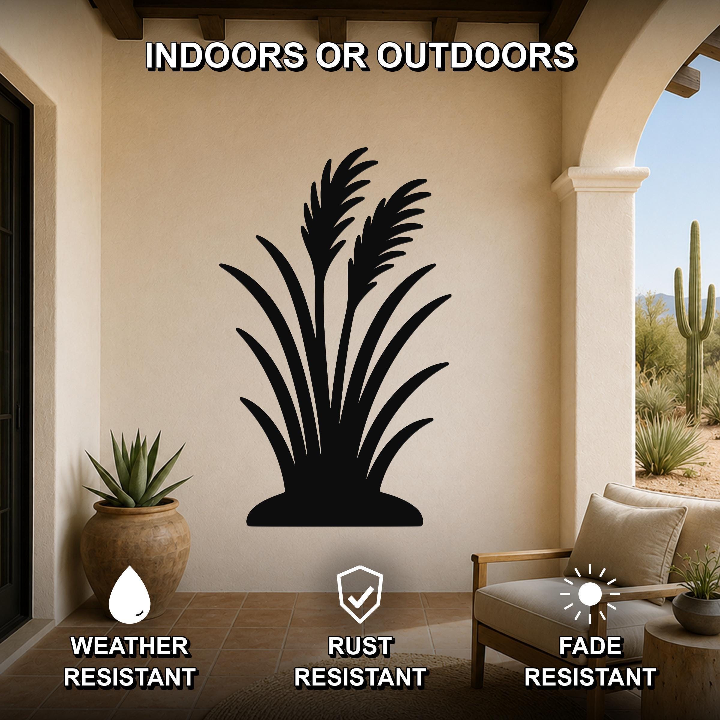 Black metal wall art of a wild grass silhouette, mounted on a beige outdoor patio wall above a potted succulent and a wooden chair.