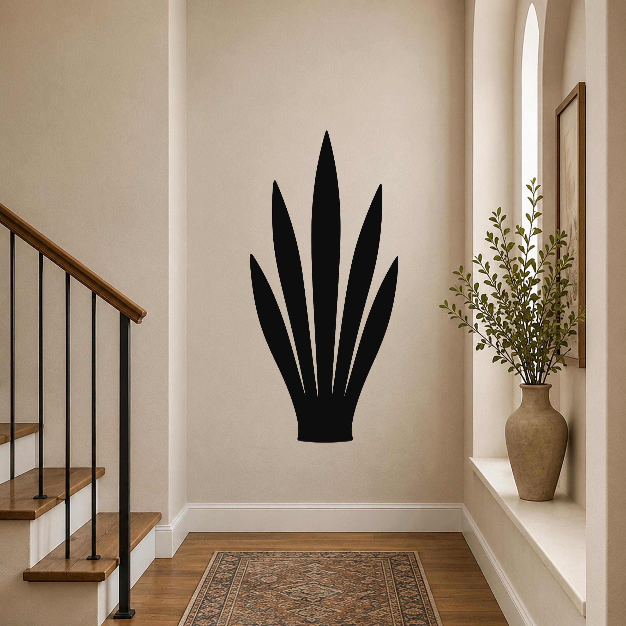 Black metal wall art in a snake plant silhouette, mounted on a hallway wall above a patterned rug near a staircase.