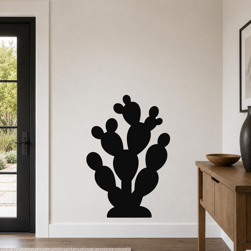 Black metal prickly pear cactus wall art with multiple rounded pads and cutout details, mounted on a light-colored wall in a modern entryway.