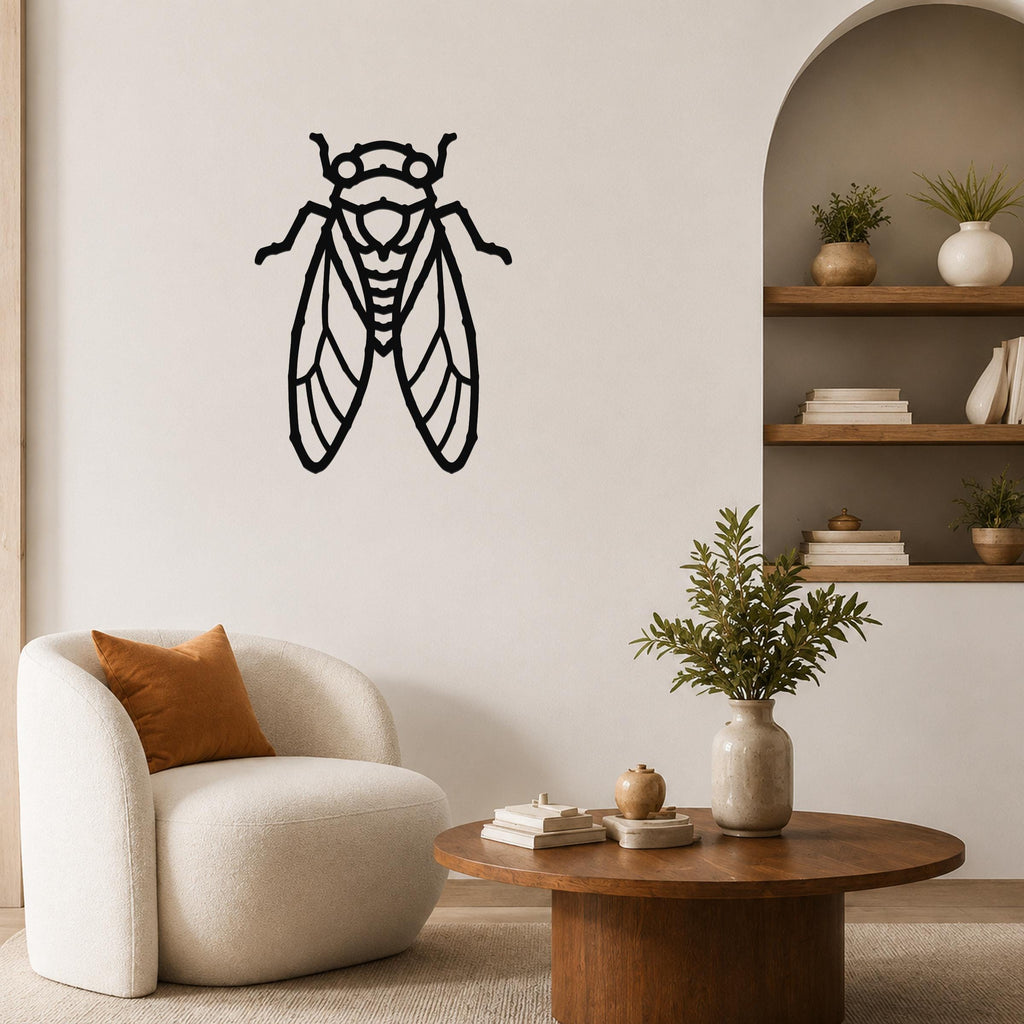 Black metal cicada wall art with detailed wing cutouts, mounted on a living room wall above a white armchair.