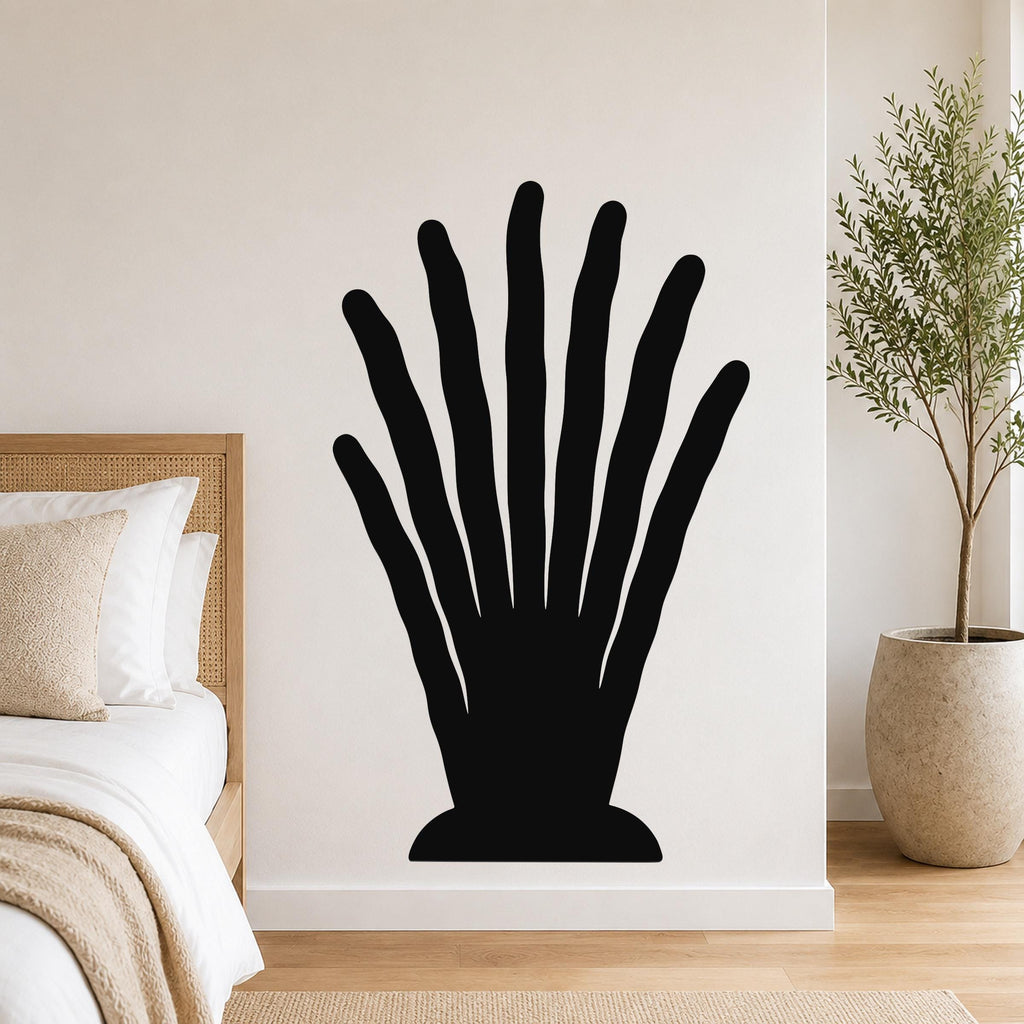 Black metal wall art in a silhouette of a hand with elongated fingers, mounted on a bedroom wall above a bed.