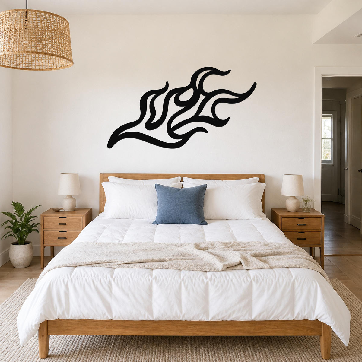 Black metal flame wall art with flowing, abstract cutouts, mounted above a bed in a bedroom.