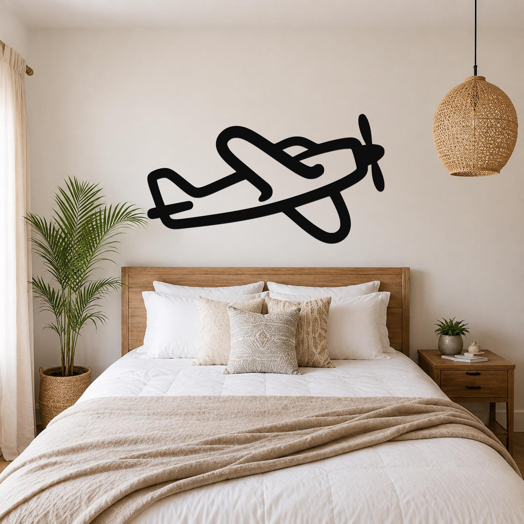 Black metal airplane wall art silhouette with propeller and wing cutouts, mounted above a wooden bed in a bedroom.