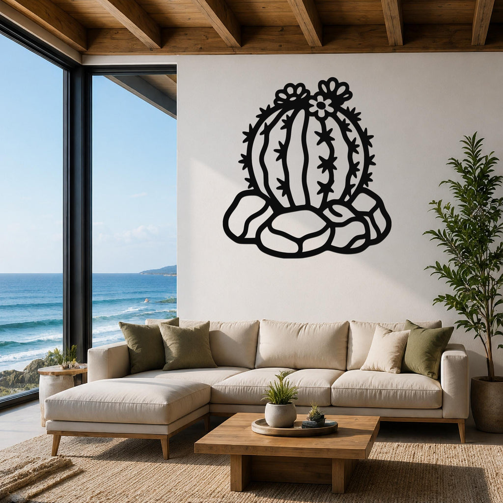 Black metal barrel cactus wall art with flower and spine cutouts, mounted on a white wall above a beige sofa in a living room with ocean views.
