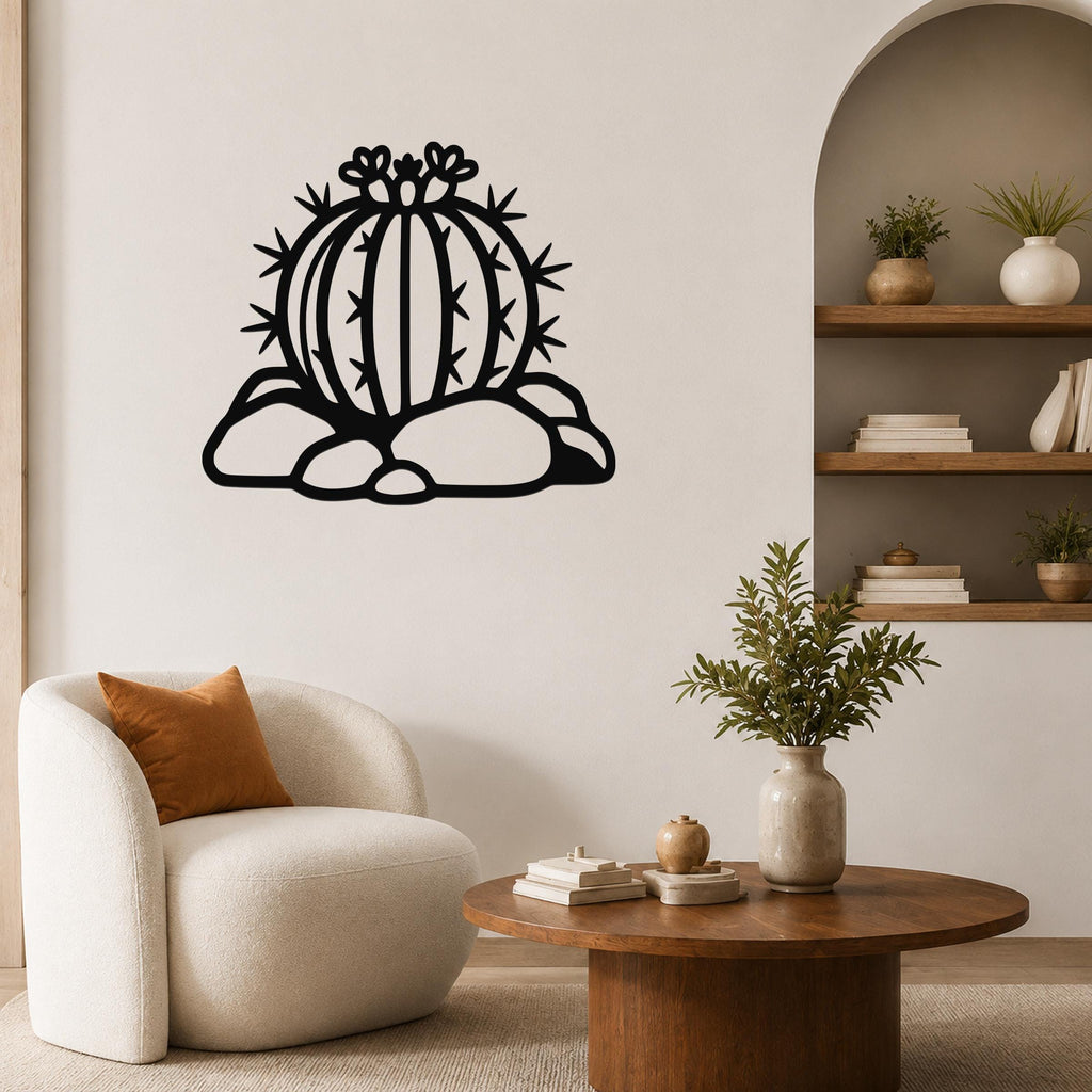Black metal barrel cactus wall sculpture with flower and spine cutouts, mounted on a living room wall above a white armchair.