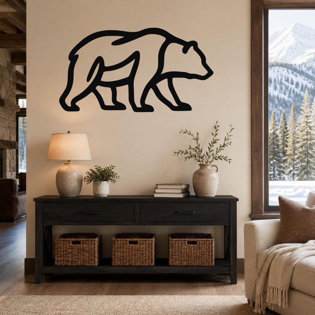 Black metal bear silhouette wall art mounted above a dark console table in a living room with a snowy mountain view.