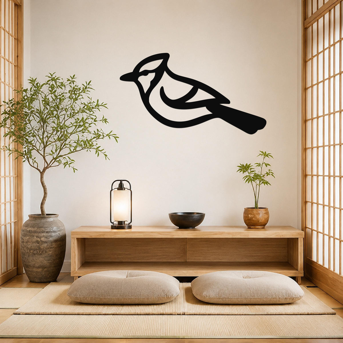 Black metal bird wall art in a silhouette style, mounted on a wall above a wooden console in a minimalist room with tatami mats and plants.