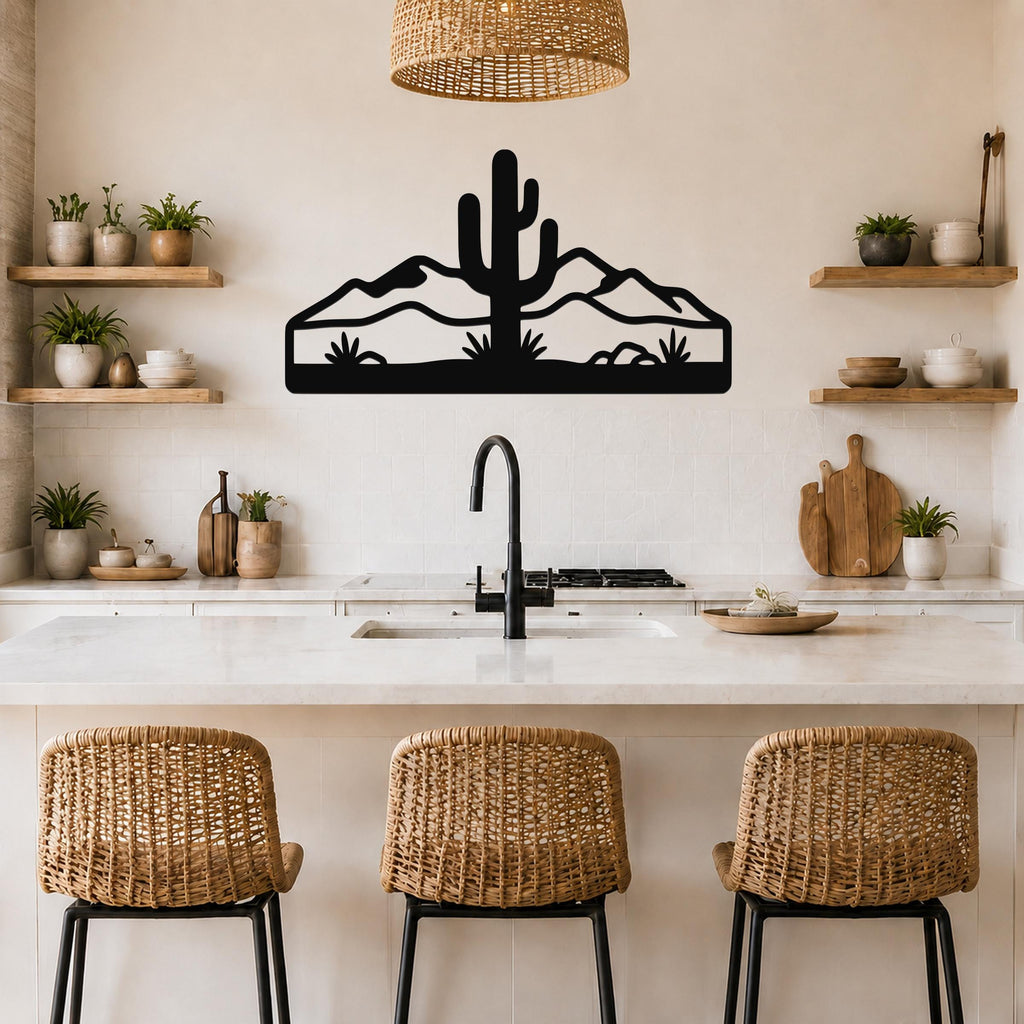Black metal wall art featuring a saguaro cactus and mountain silhouette, mounted above a kitchen counter with wicker bar stools.