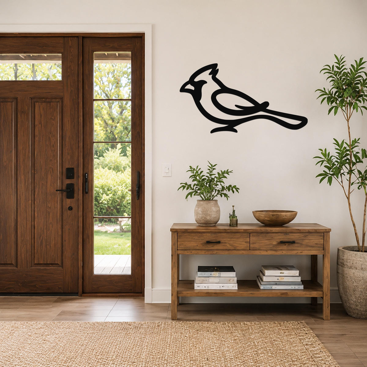 Black metal cardinal wall art in a bold silhouette style, mounted on a light-colored wall above a wooden console table in a entryway.