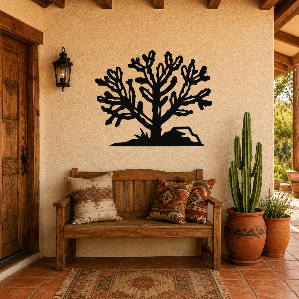 Black metal Cholla cactus wall art with branching cutouts, mounted on a stucco wall above a wooden bench in a patio entryway.
