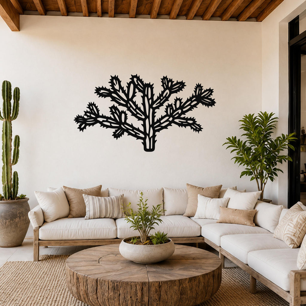 Black metal Cholla cactus wall art with intricate branch cutouts, mounted on a living room wall above a white sofa.