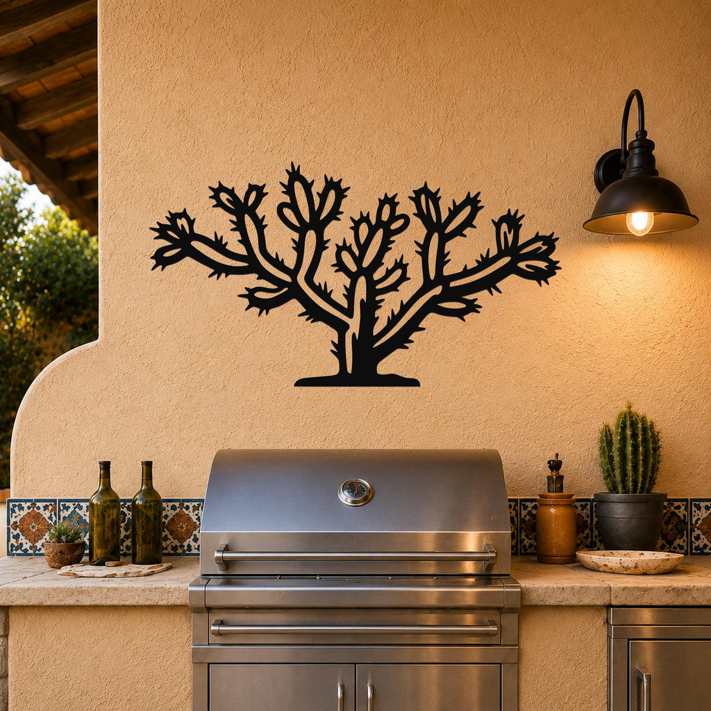 Black metal Cholla cactus wall art with detailed branch and spine cutouts, mounted on a stucco wall above an outdoor grill.