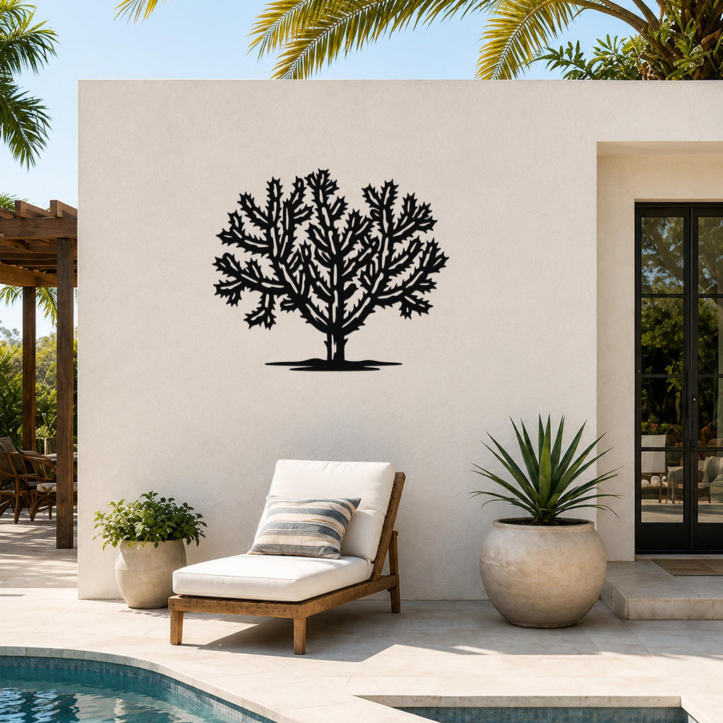 Black metal Cholla cactus wall art with intricate branching cutouts, mounted on an outdoor patio wall above a lounge chair.