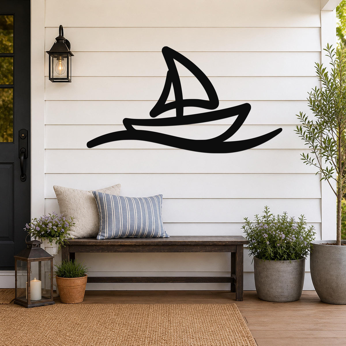 Black metal sailboat wall art with wave cutouts, mounted on a white shiplap wall above a wooden bench on a porch.