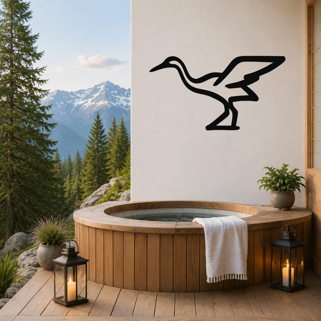 Black metal crane wall art silhouette mounted on a white wall above a wooden hot tub on a mountain-view deck.
