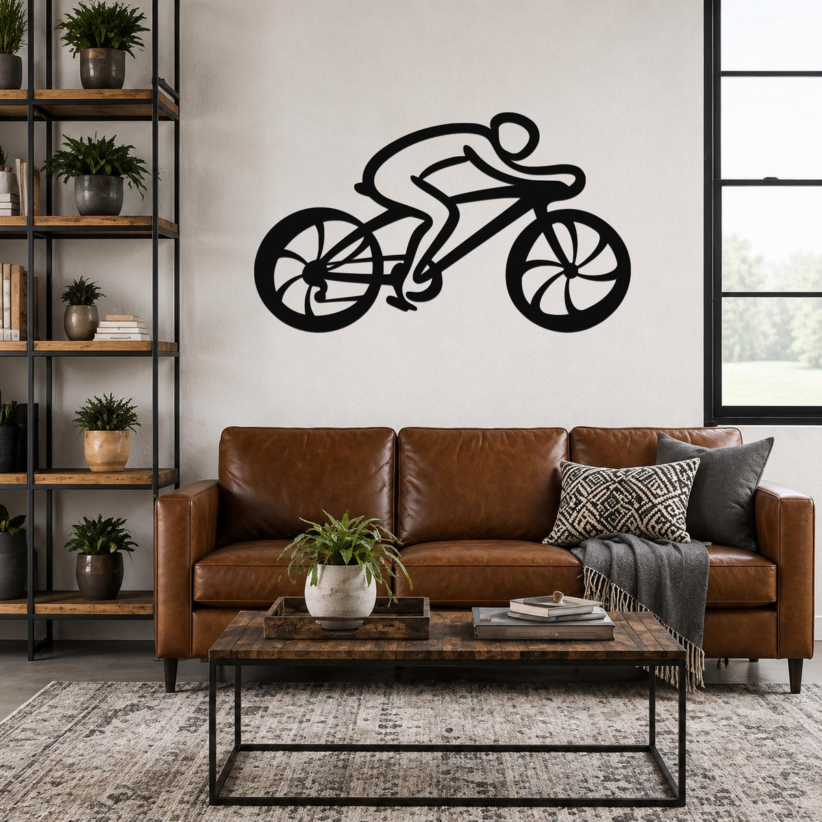 Black metal wall art silhouette of a cyclist on a bike, mounted above a brown leather sofa in a living room.