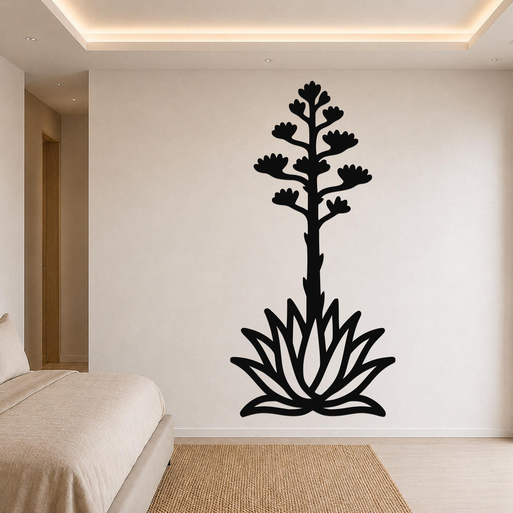 Black metal wall art silhouette of a blooming agave plant with a tall stem and flower spikes, mounted on a bedroom wall above a bed.