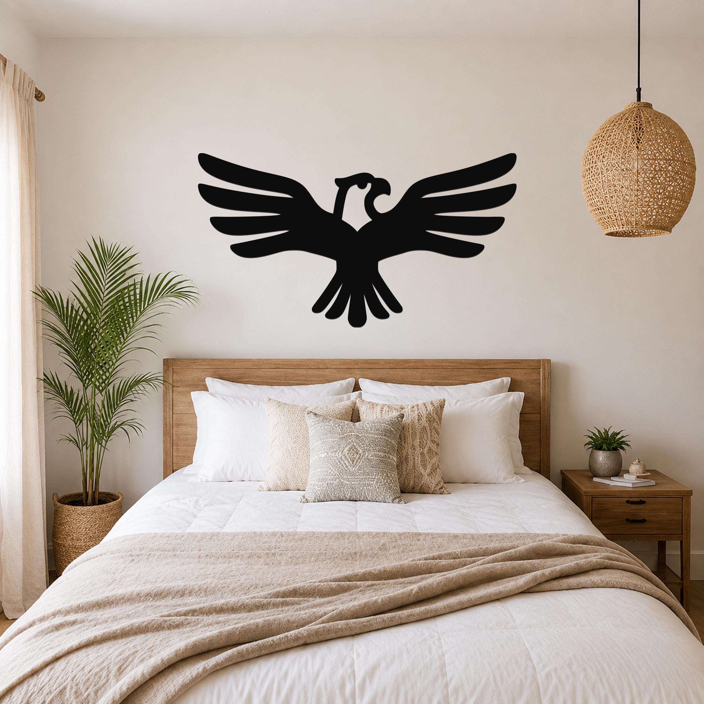 Black metal eagle wall art with outstretched wings and a cutout head, mounted above a wooden bed in a neutral bedroom.