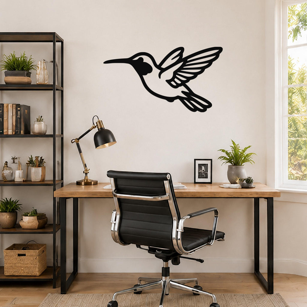 Black metal hummingbird wall art with motion-line cutouts, mounted above a wooden desk in a home office.