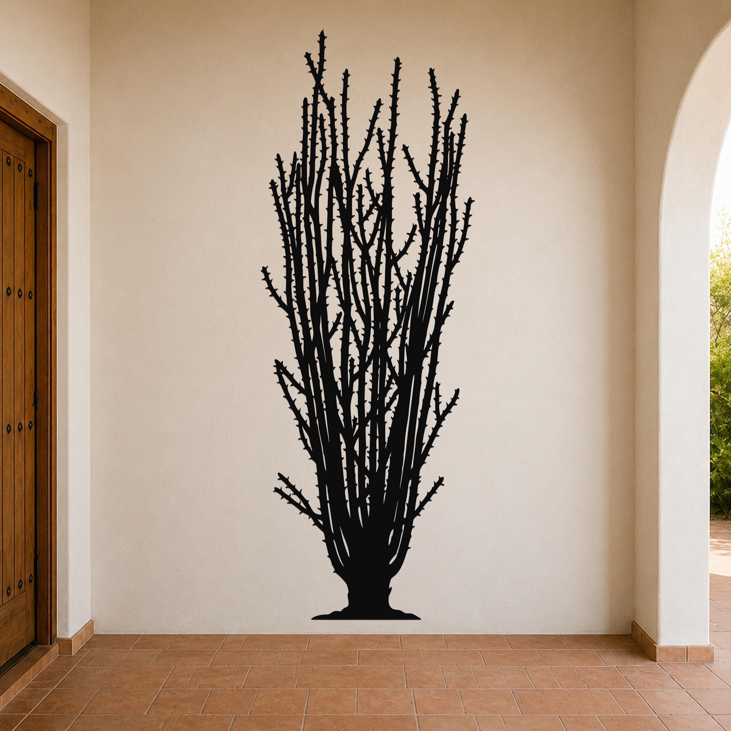 Black metal wall art silhouette of a tall ocotillo cactus with spiny branches, mounted on a beige interior wall above a tiled floor.