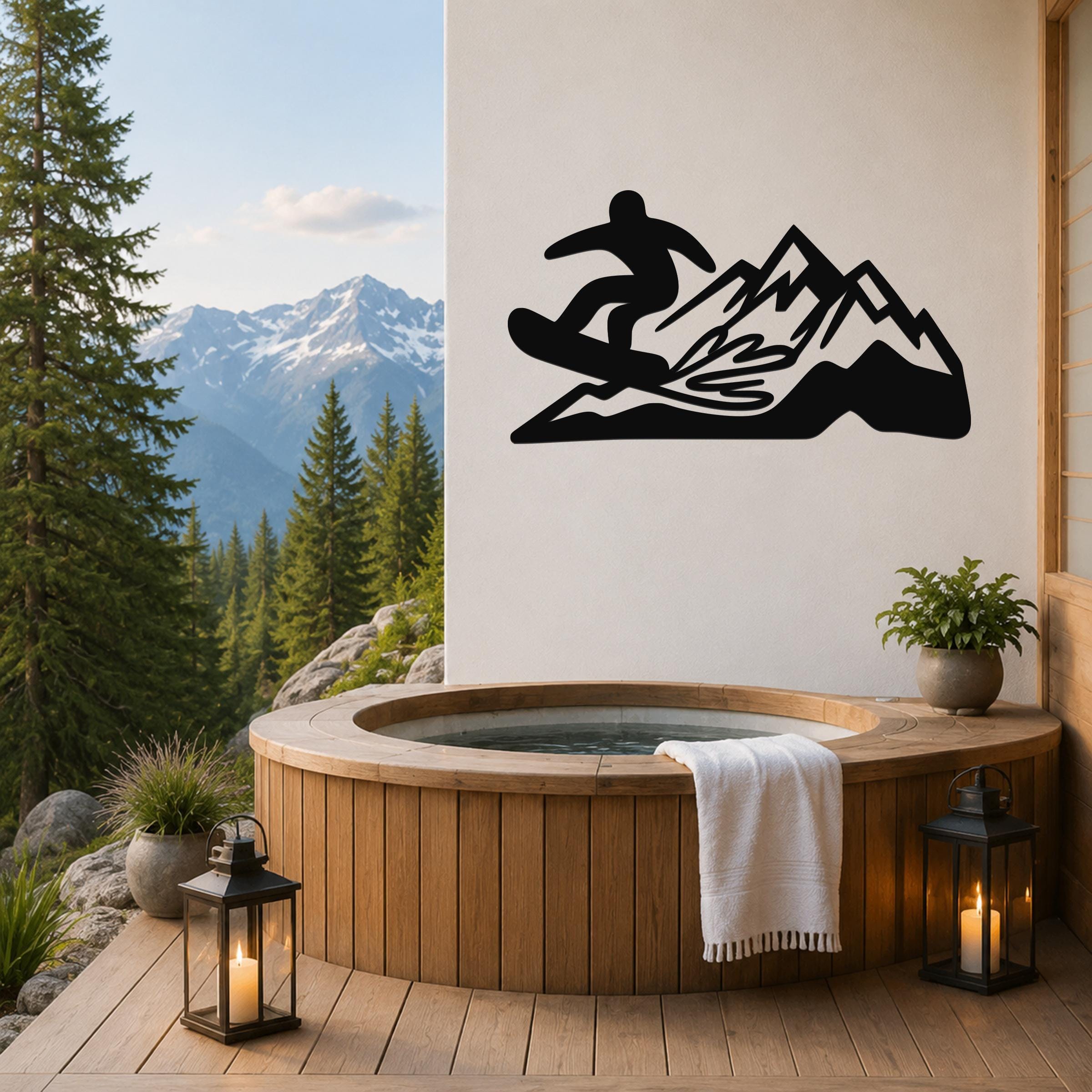 Black metal wall art featuring a snowboarder silhouette on a mountain, mounted on a white wall above a wooden hot tub on a deck with a mountain view.