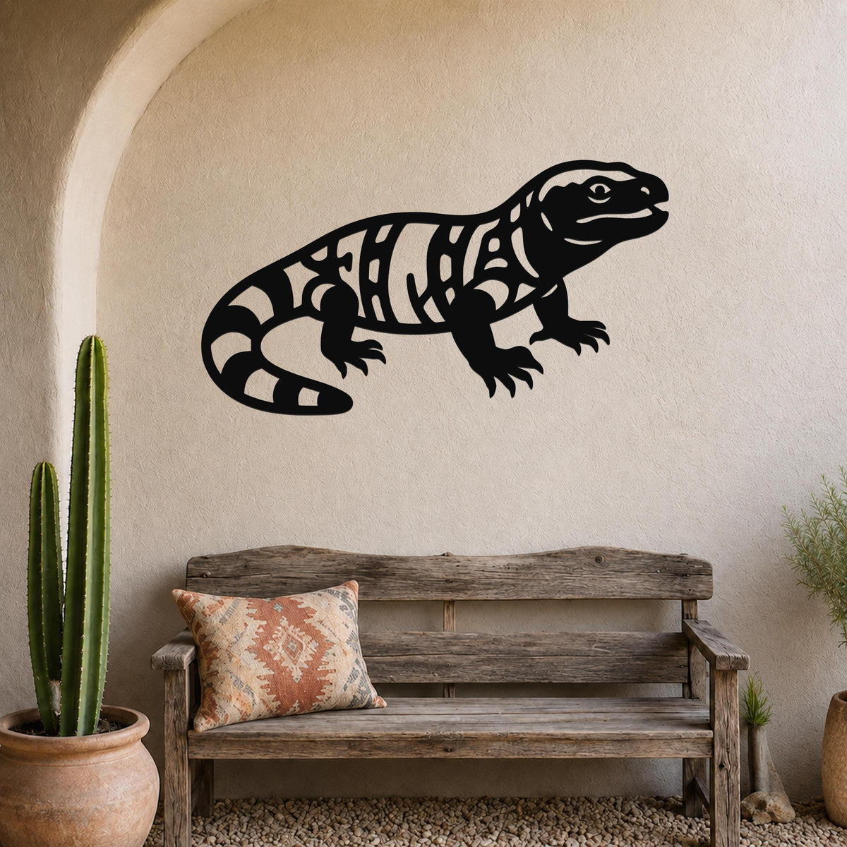 Black metal Gila monster wall art with intricate internal cutouts, mounted on a textured beige wall above a rustic wooden bench in a southwestern-style entryway.
