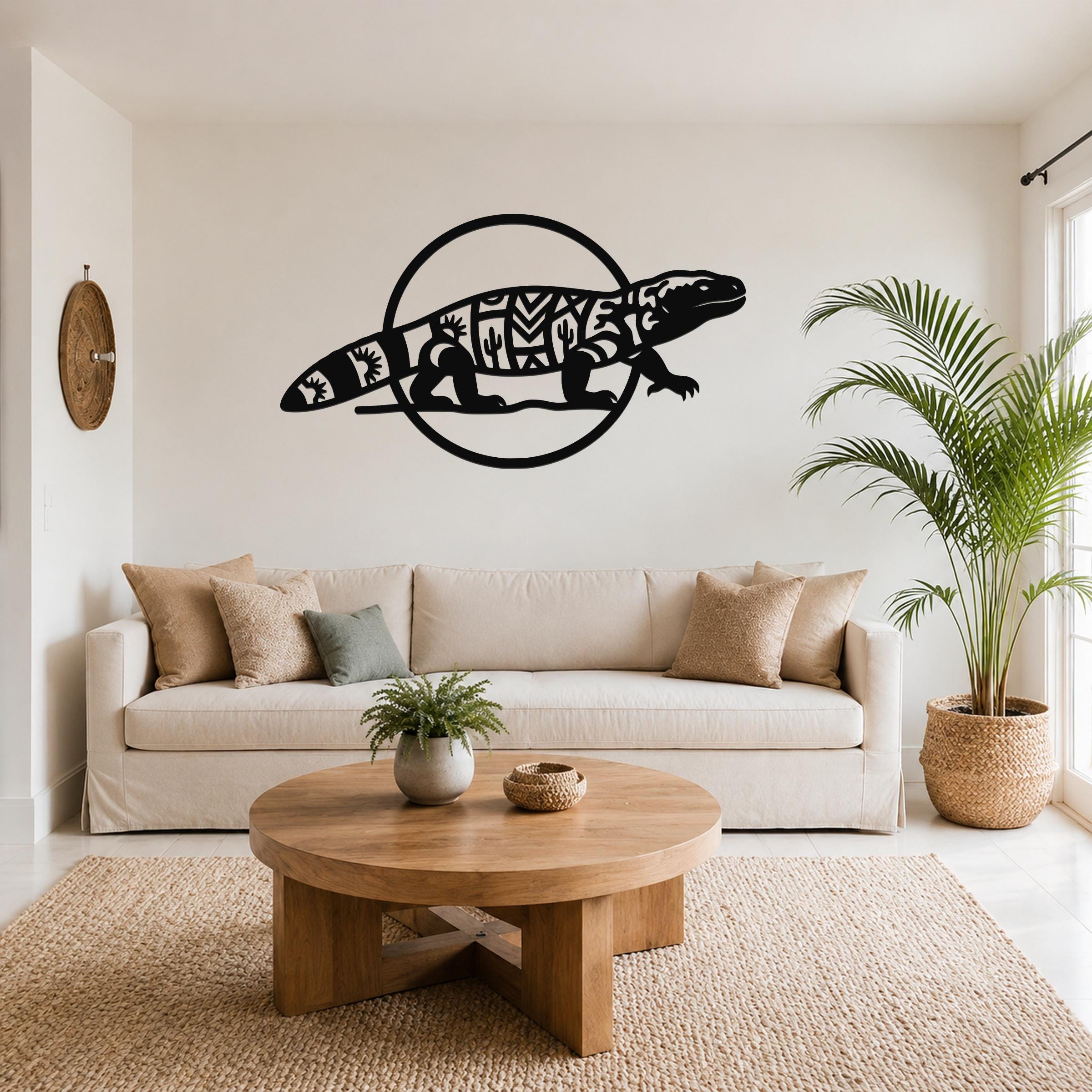 Black metal Gila monster wall art with geometric and cactus cutouts, mounted above a beige sofa in a living room.