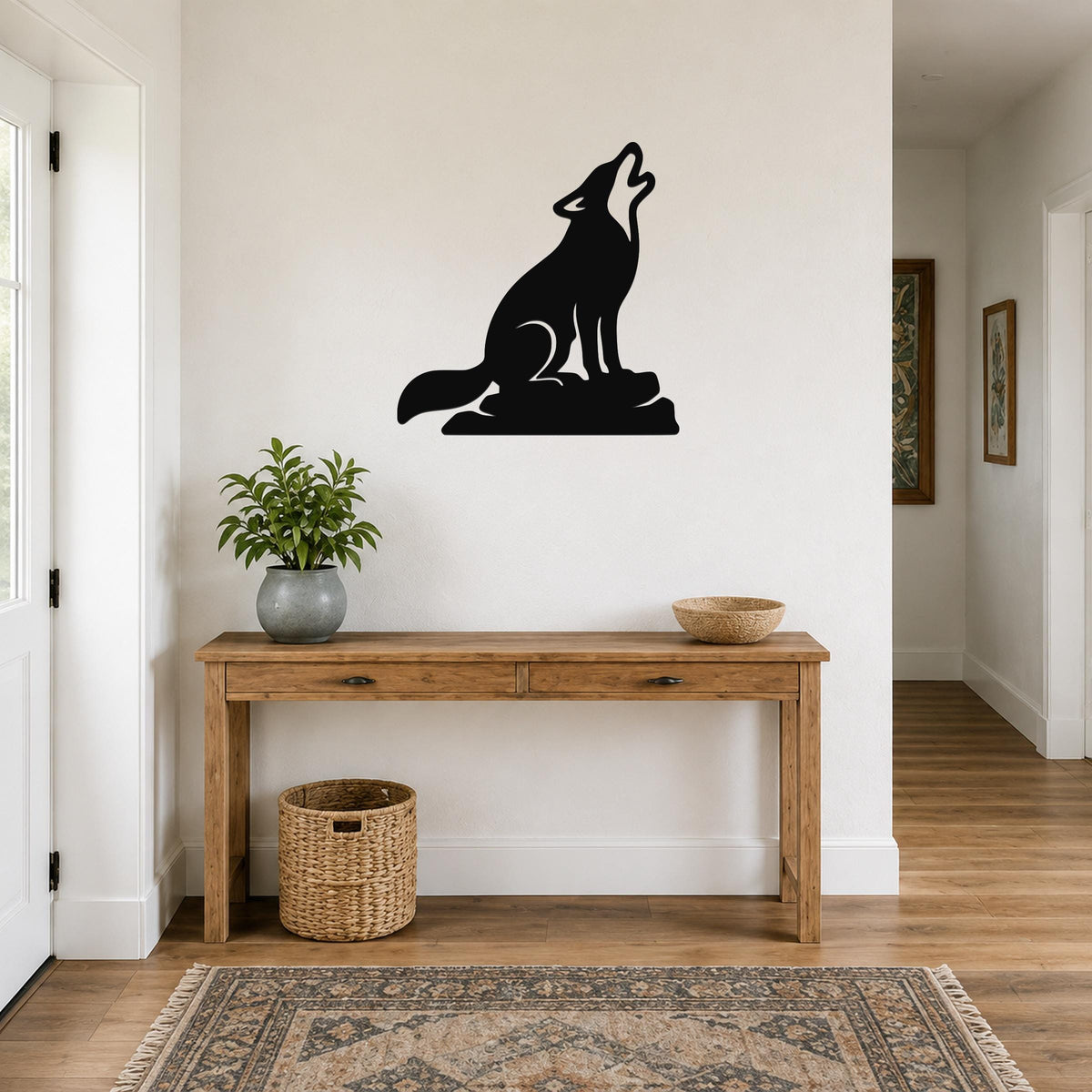Black metal coyote wall art in a howling silhouette, mounted above a wooden console table in a hallway.