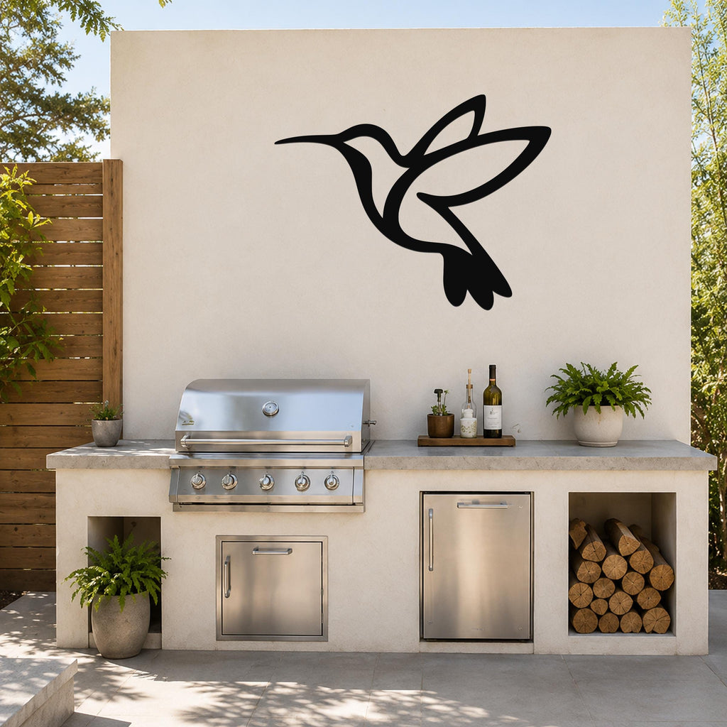 Black metal hummingbird wall art silhouette mounted on an outdoor kitchen wall above a stainless steel grill and counter.