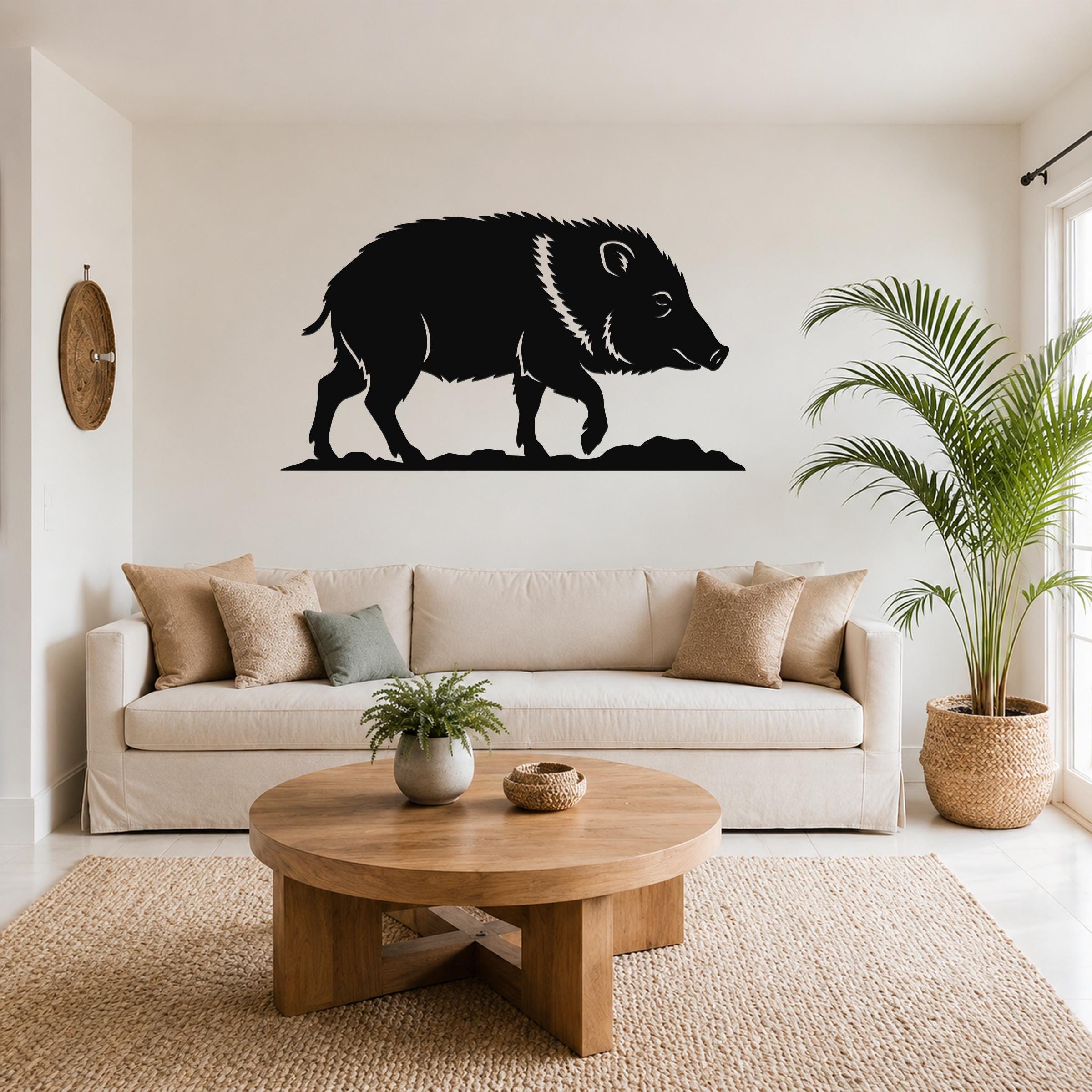 Black metal javelina wall art silhouette with white line detailing, mounted above a beige sofa in a living room.