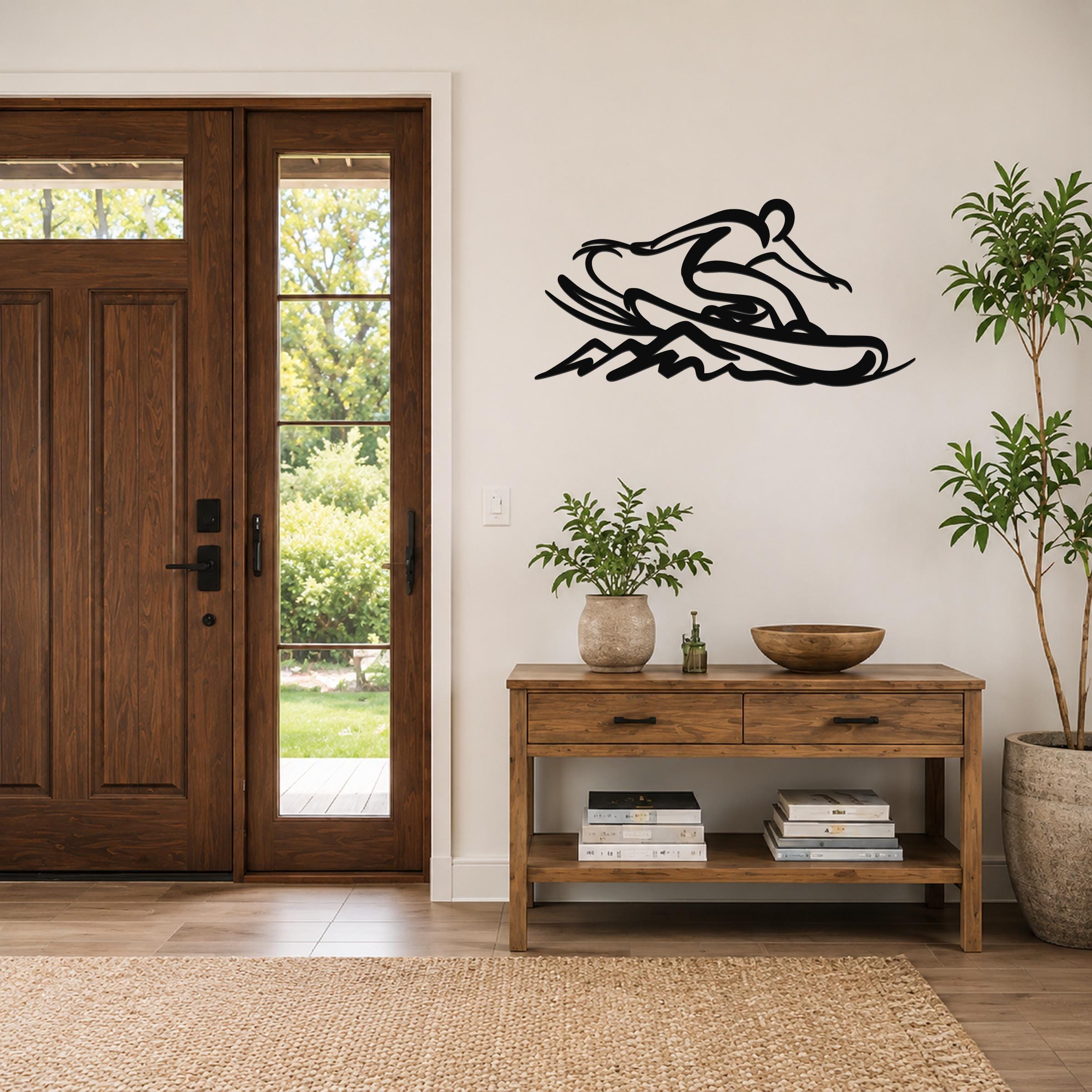 Black metal wall art of a snowboarder silhouette with motion lines, mounted on a wall above a wooden console table in a living room.