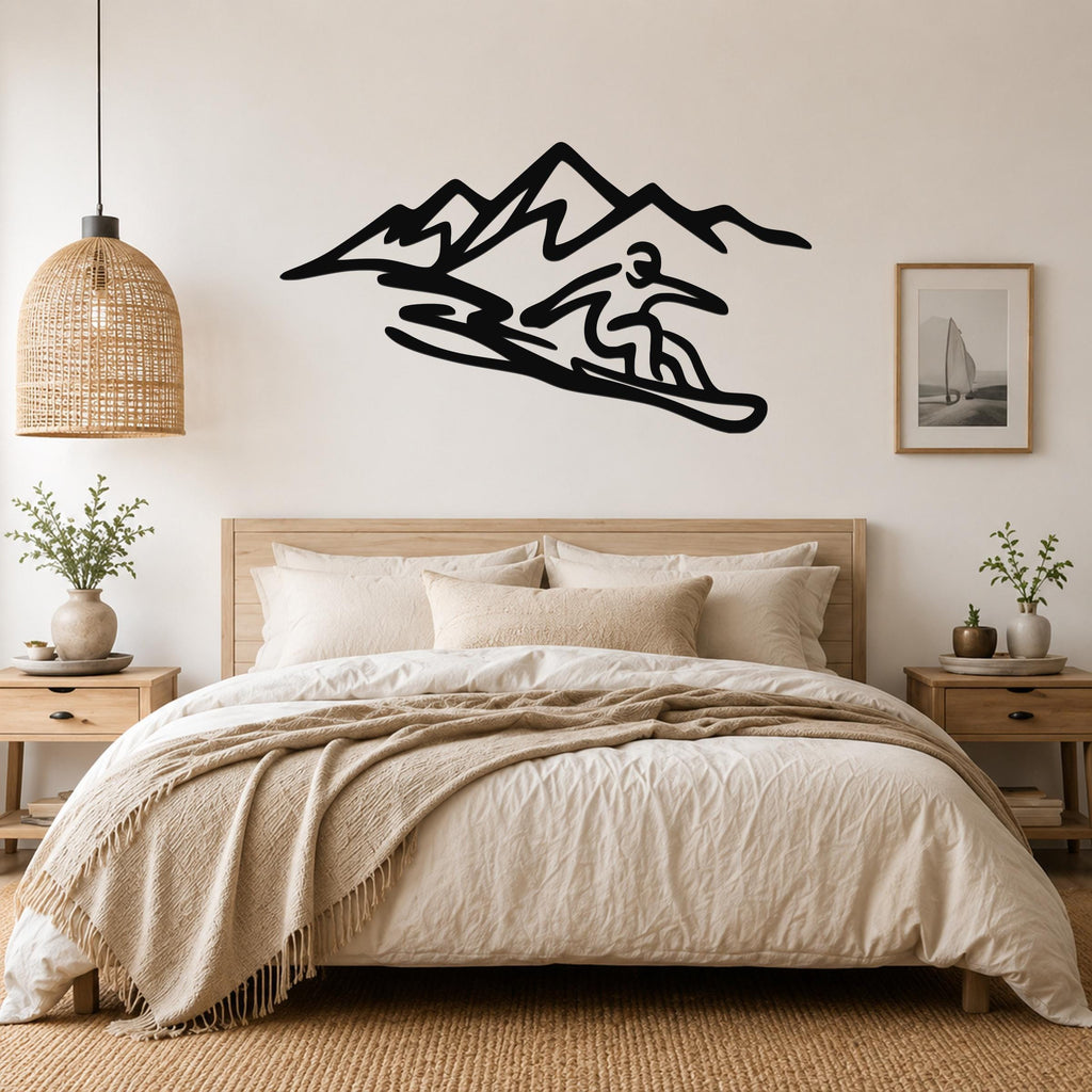Black metal wall art silhouette of a snowboarder in motion with mountain peaks, mounted above a bed in a neutral bedroom.