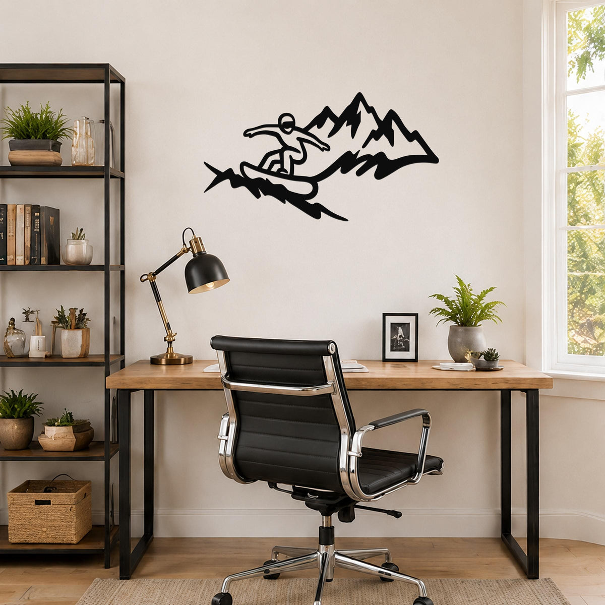 Black metal wall art featuring a snowboarder silhouette in motion above mountain peaks, mounted on a wall above a wooden desk in a home office.