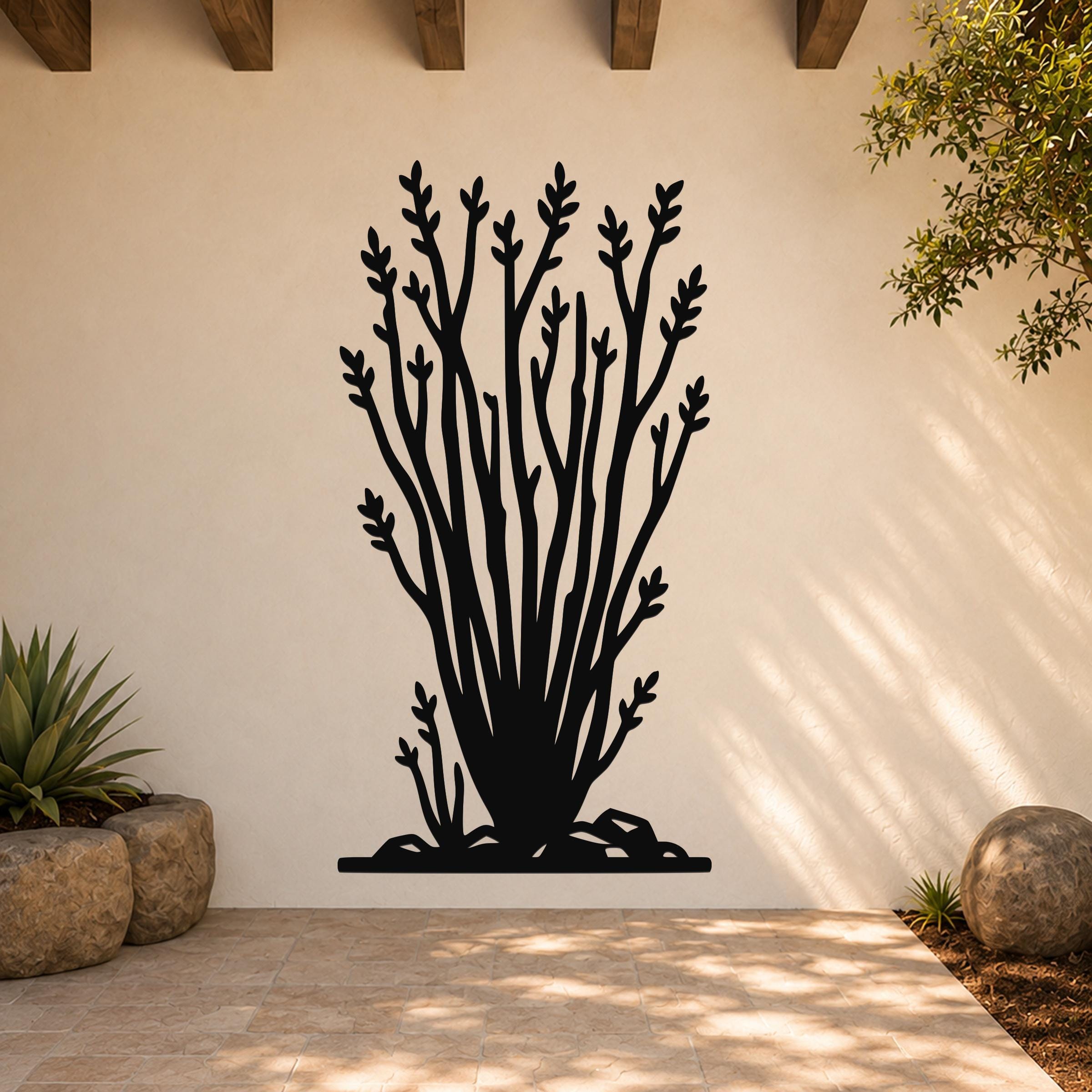 Black metal wall art cutout of an ocotillo plant with branching stems and leaf clusters, mounted on a light-colored outdoor wall above a tiled patio.