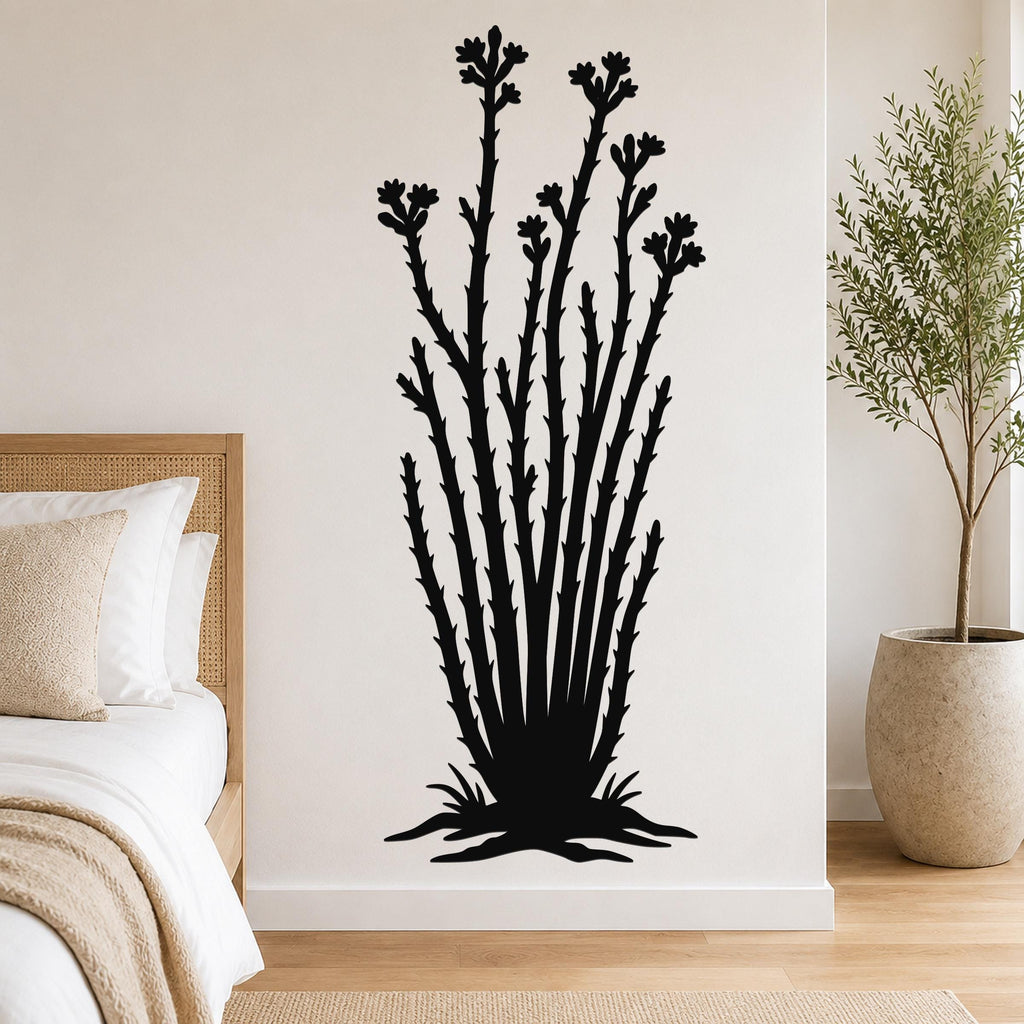 Black metal ocotillo wall art with flower and branch cutouts, mounted on a bedroom wall above a bed.