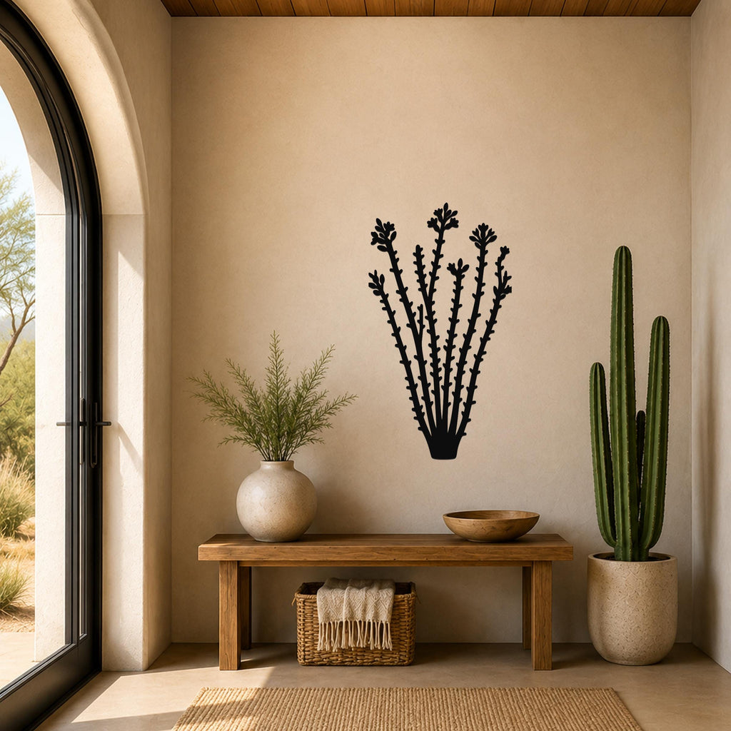 Black metal ocotillo wall art with spiky branch cutouts, mounted on a beige wall above a wooden bench in a sunlit entryway.