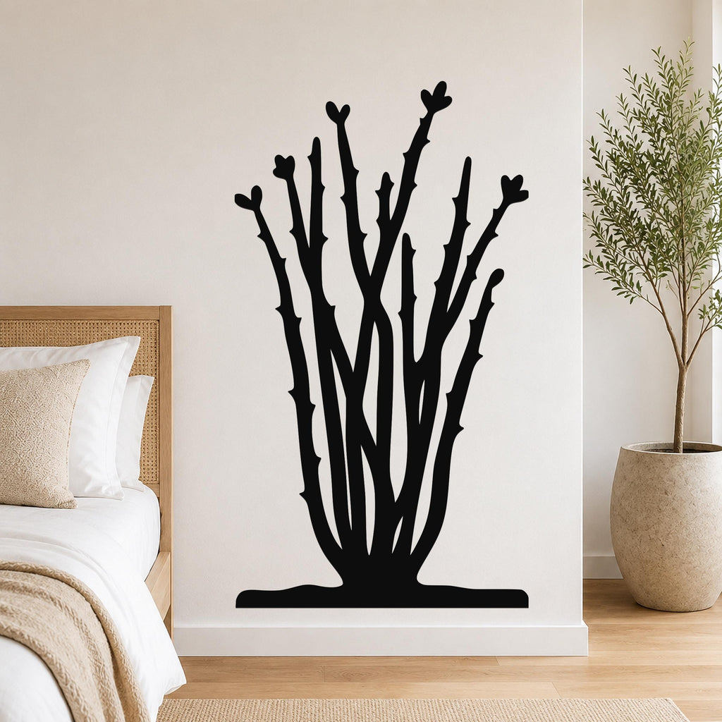 Black metal ocotillo wall art with branching stems and heart-shaped tips, mounted on a bedroom wall above a bed.