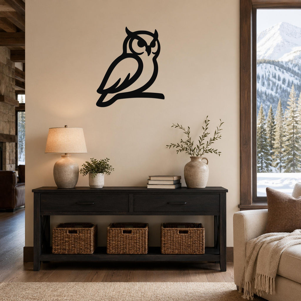 Black metal owl wall art in a silhouette style, mounted on a beige wall above a dark wood console table in a living room.