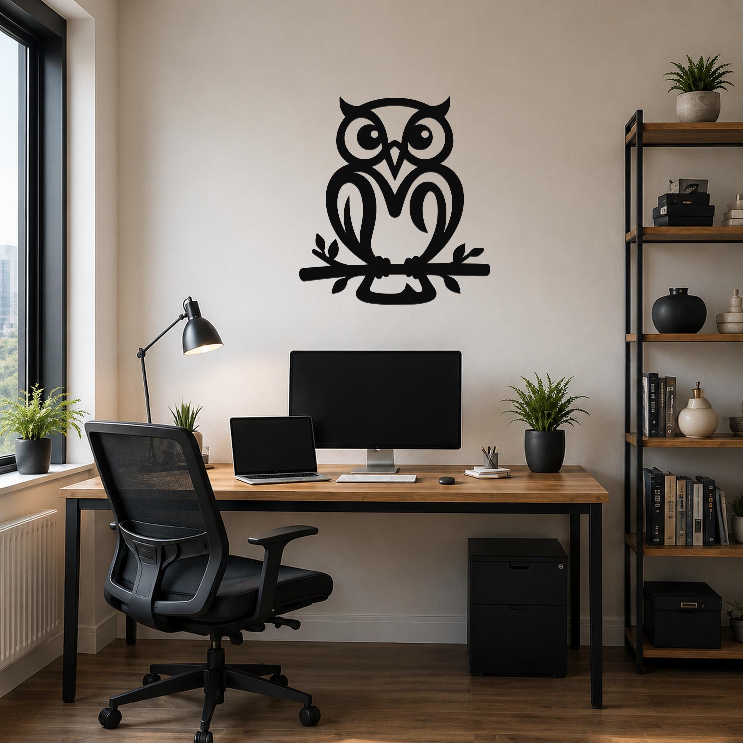 Black metal owl wall art cutout perched on a branch, mounted above a wooden desk in a home office.