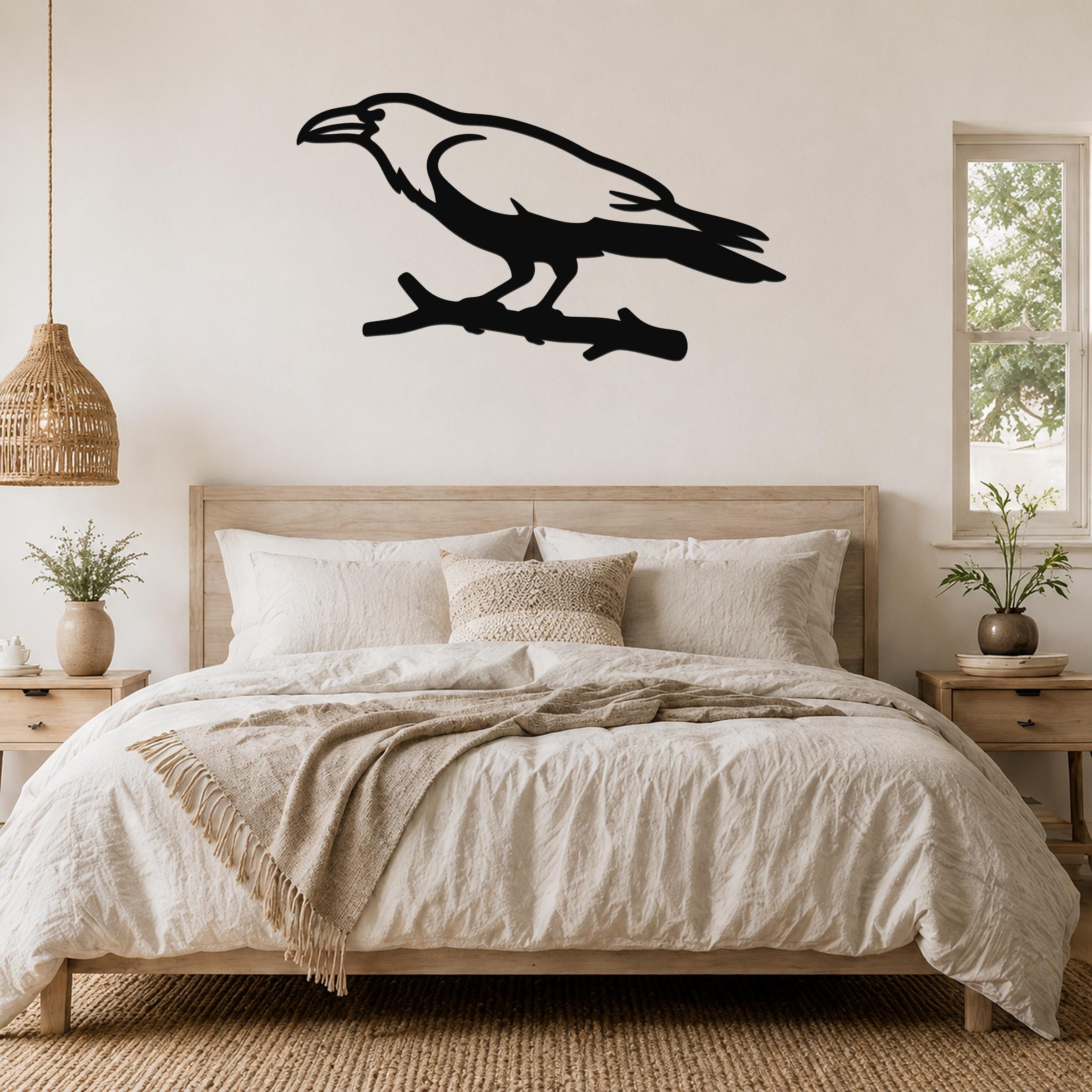 Black metal raven wall art silhouette perched on a branch, mounted above a bed in a neutral bedroom.